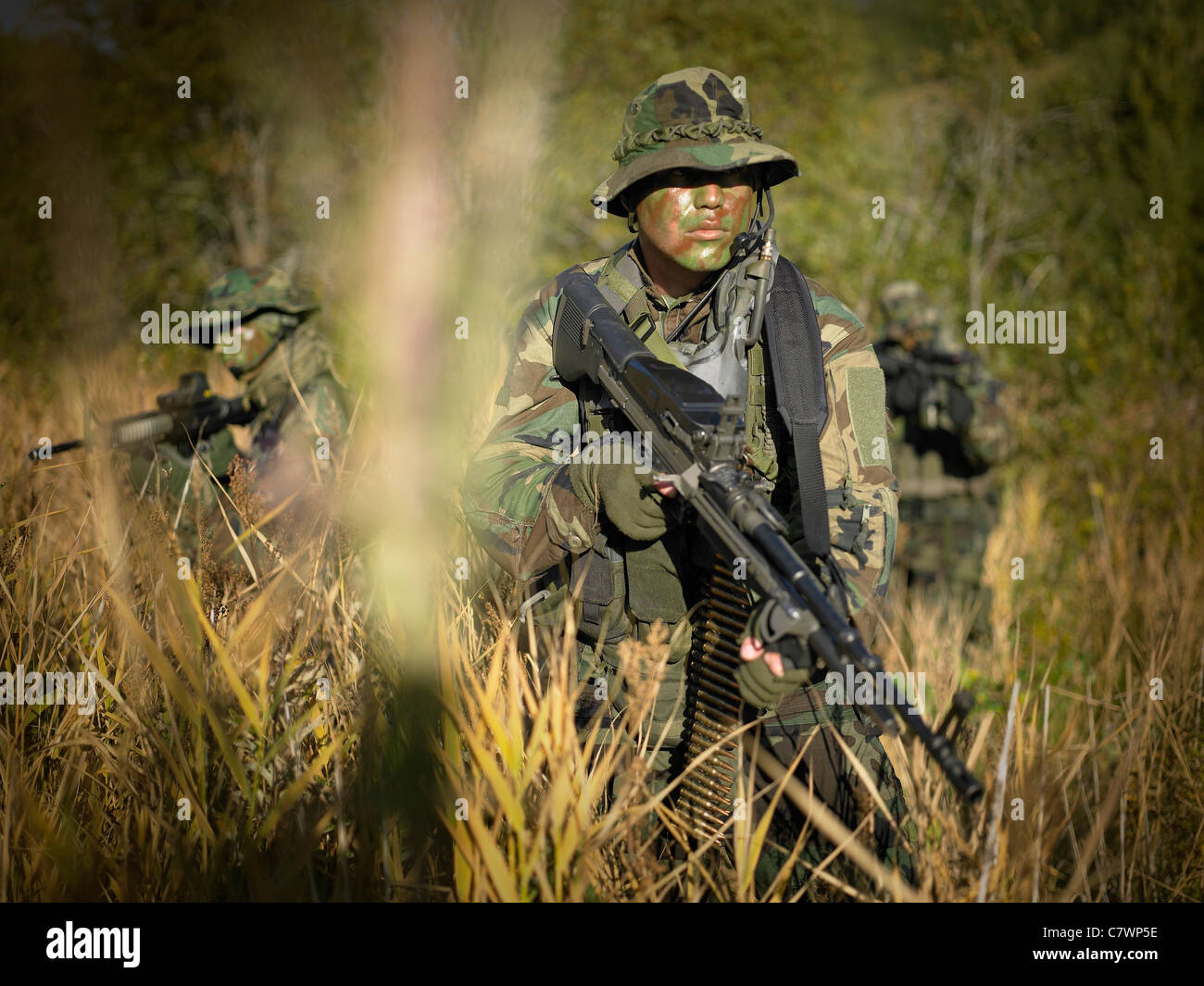 U.S. Navy SEALs gehen während der Kampfhandlungen durch hohe Gräser. Stockfoto