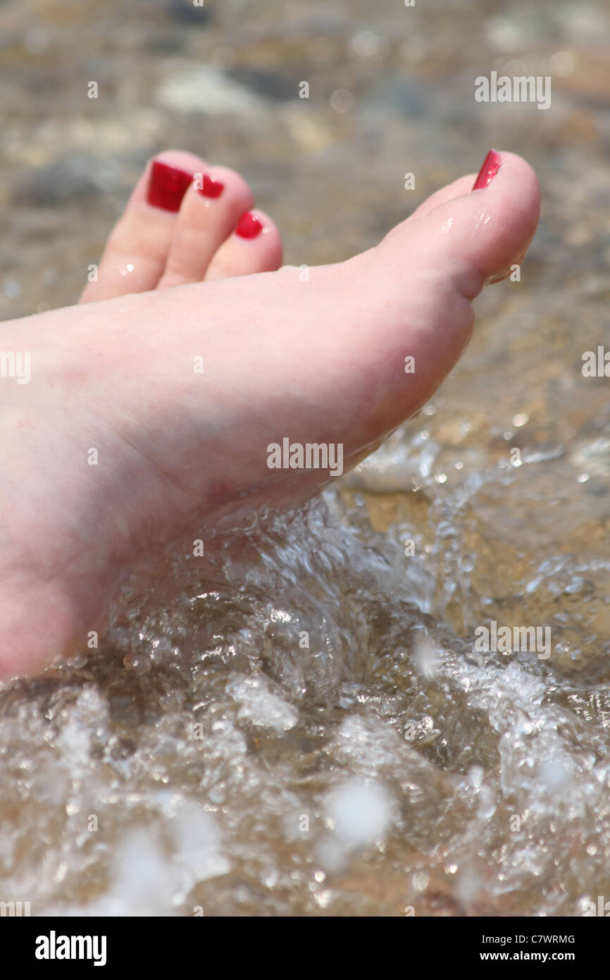 Womens gemalt Zehen im Wasser mit Wellen spritzen Stockfoto