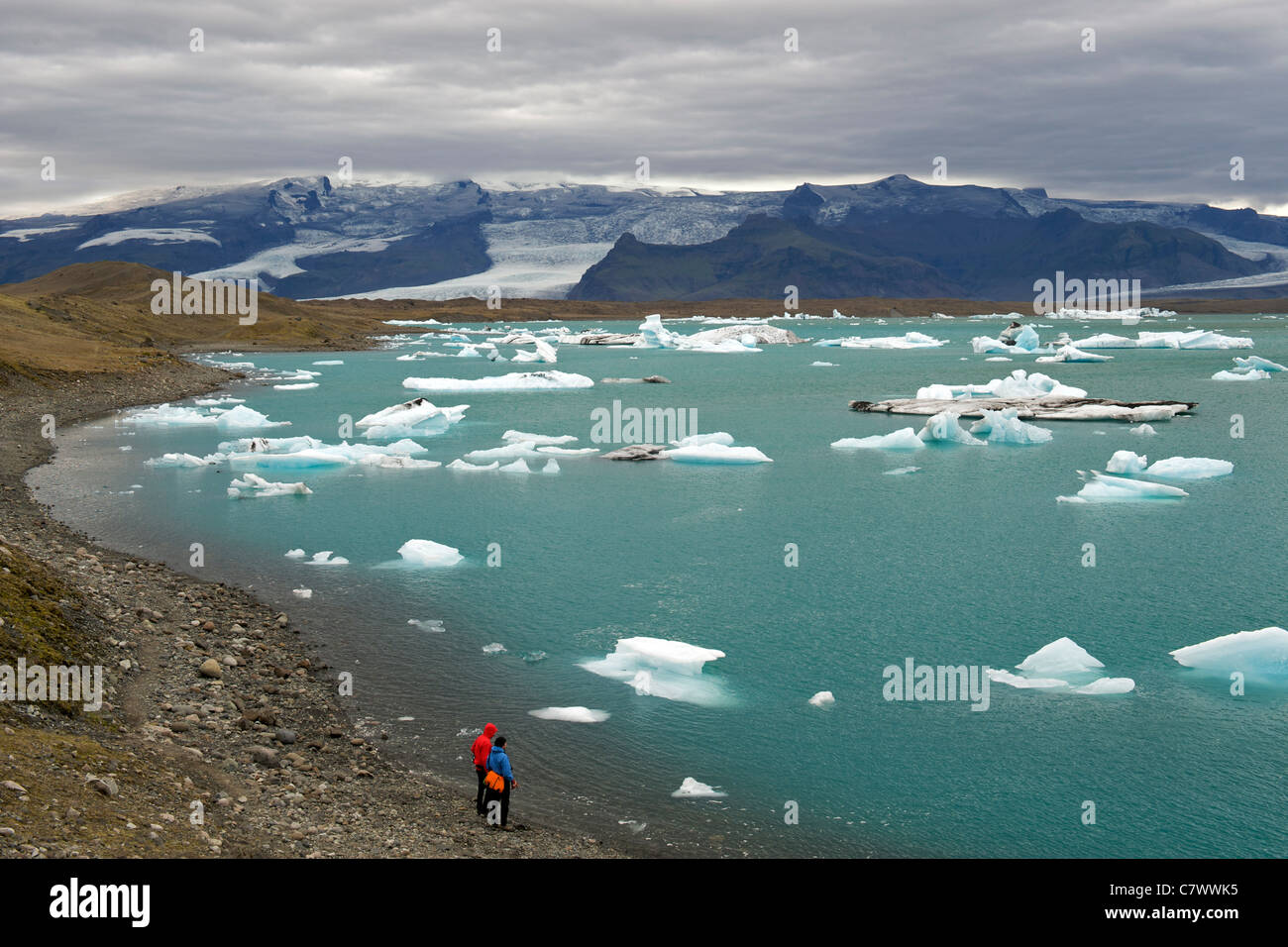 Touristen, die Eisberge schwimmen im Jokullsarlon-See am Fuße des massiven Vatnajökull-Gletscher im Südosten Islands beobachten. Stockfoto