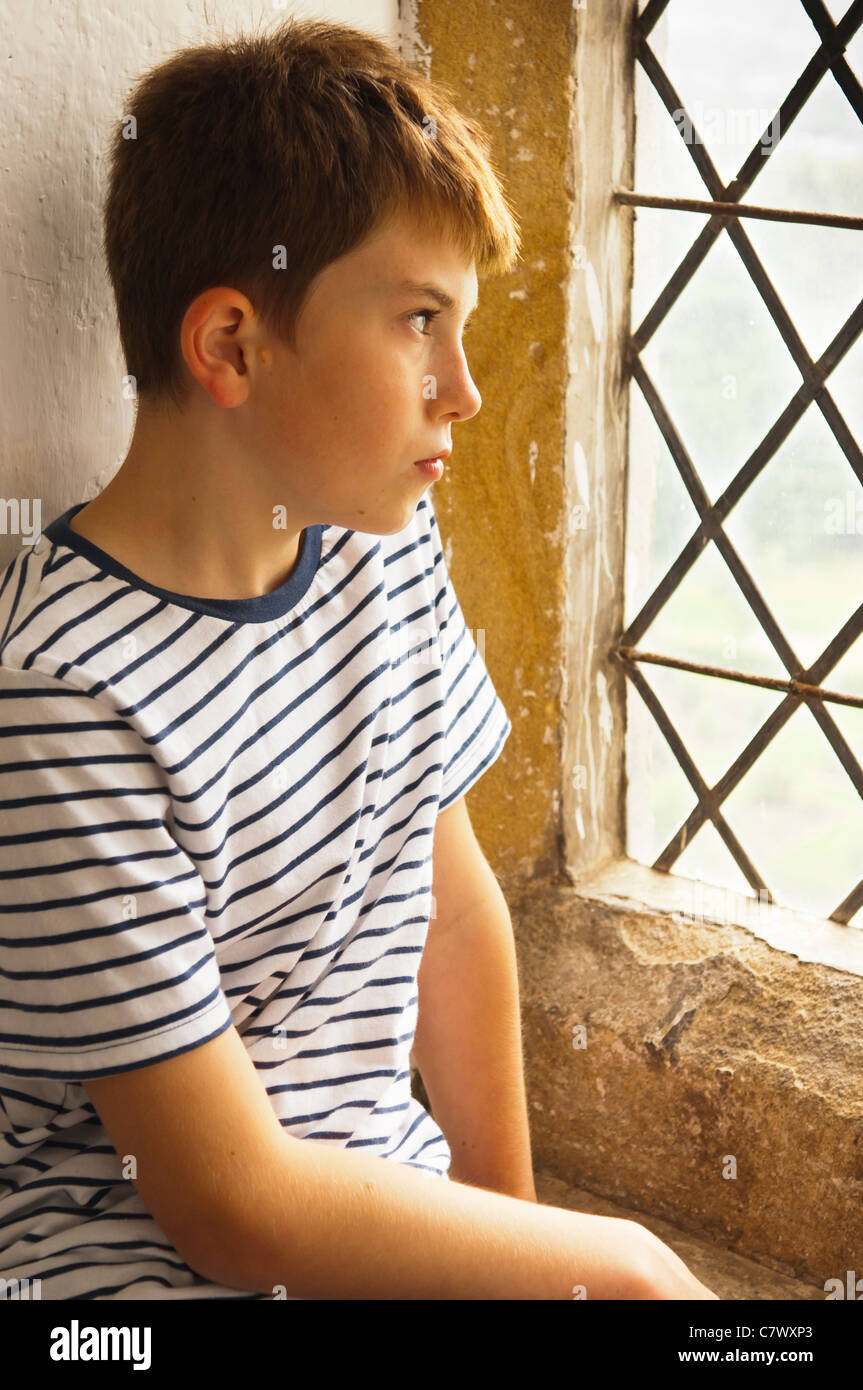 Ein kleiner Junge schaut aus dem Fenster bei Bolton Castle in der Nähe von Leyburn in North Yorkshire, England, Großbritannien, Uk Stockfoto