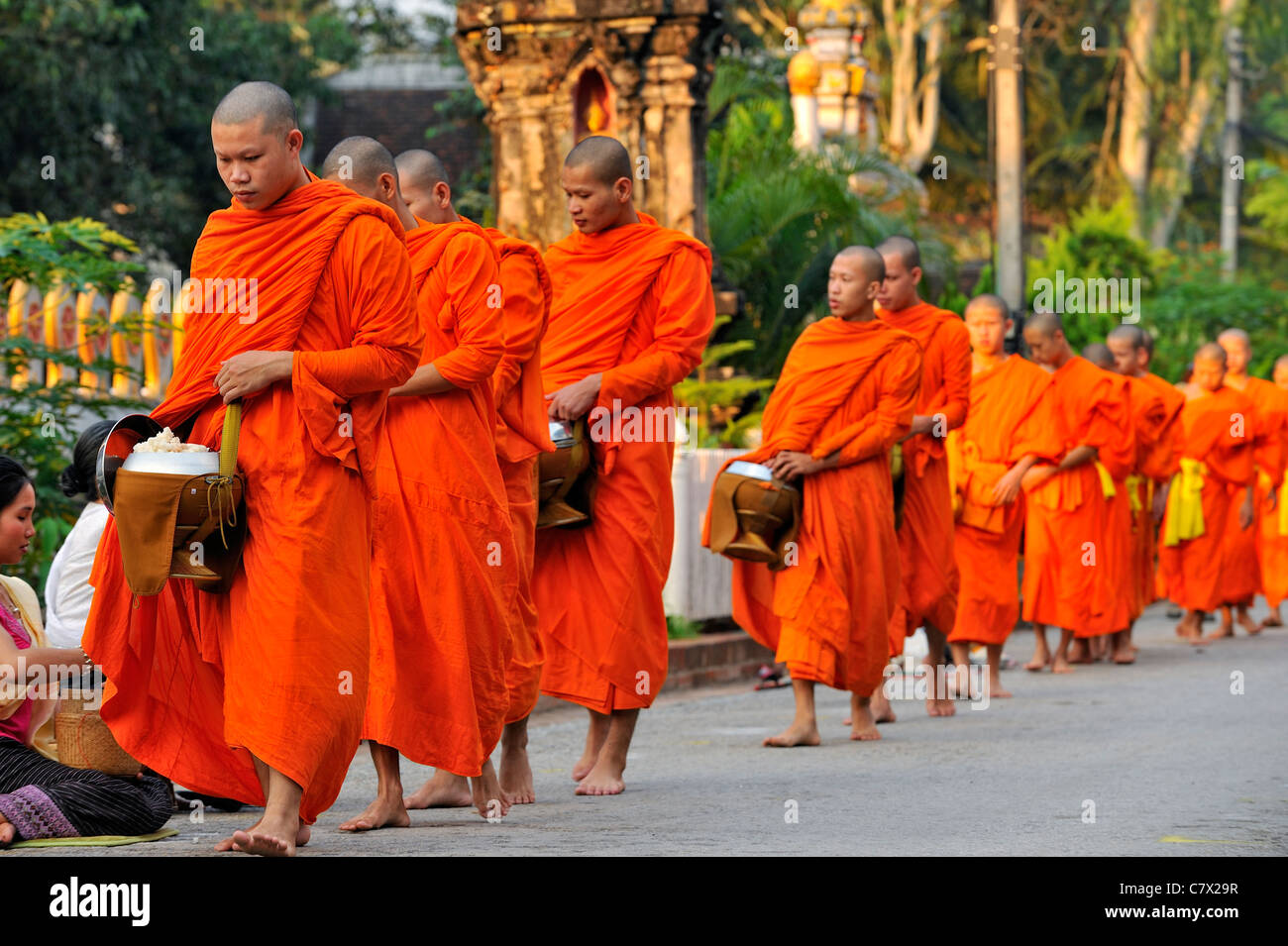 Buddhistische Mönche wandern mit Mönch Schüssel Essen am Morgen zu sammeln. UNESCO Weltkulturerbe Welt Erbe Stadt Luang Prabang Stockfoto