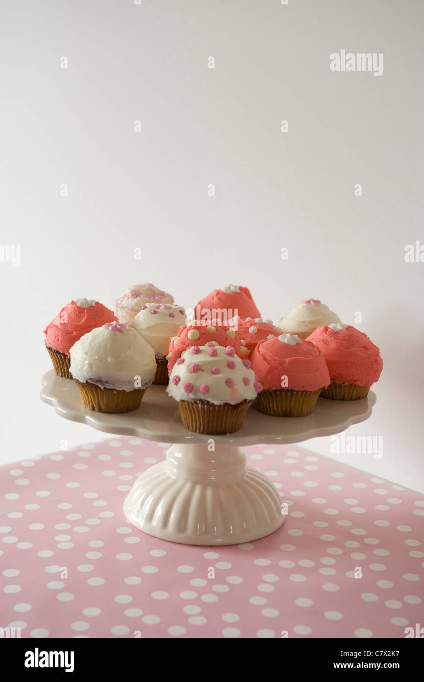 Cupcakes frosted Pink und Weiß auf einem Kuchen Platte und Rosa polkadot vorne, mit weißen redaktionellen Platz im Hintergrund Stockfoto