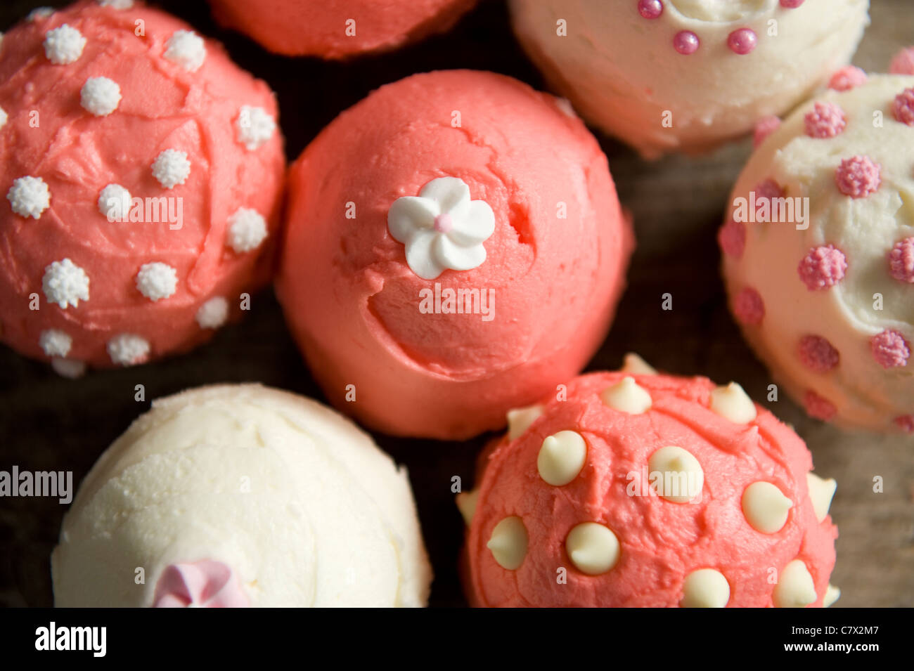 Cupcakes frosted Pink und Weiß in verschiedenen Mustern auf einem Kuchen Platte wieder leuchtet Stockfoto