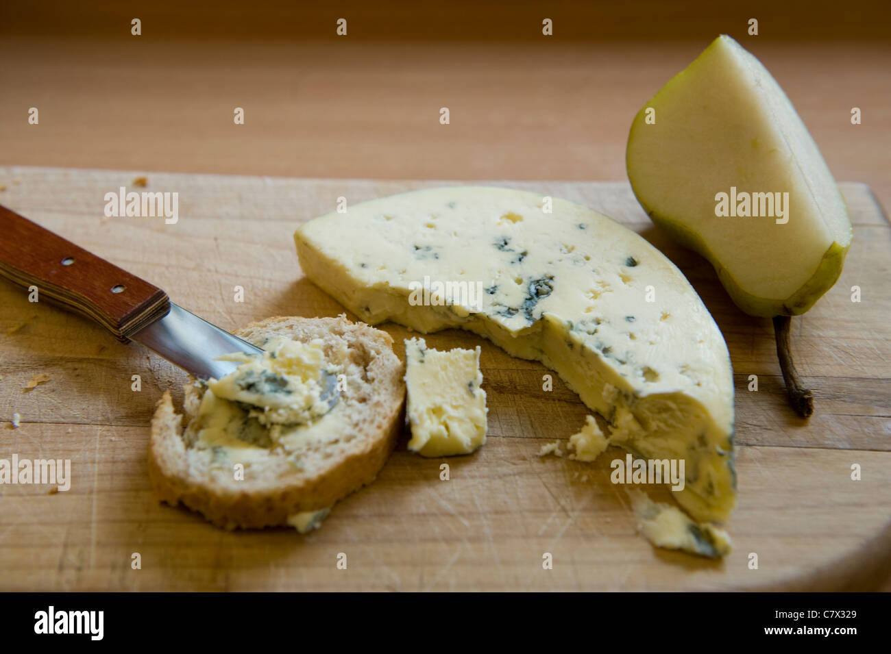 Bluecheese mit Birne und Brot auf einem Holzbrett mit Hintergrundbeleuchtung Stockfoto