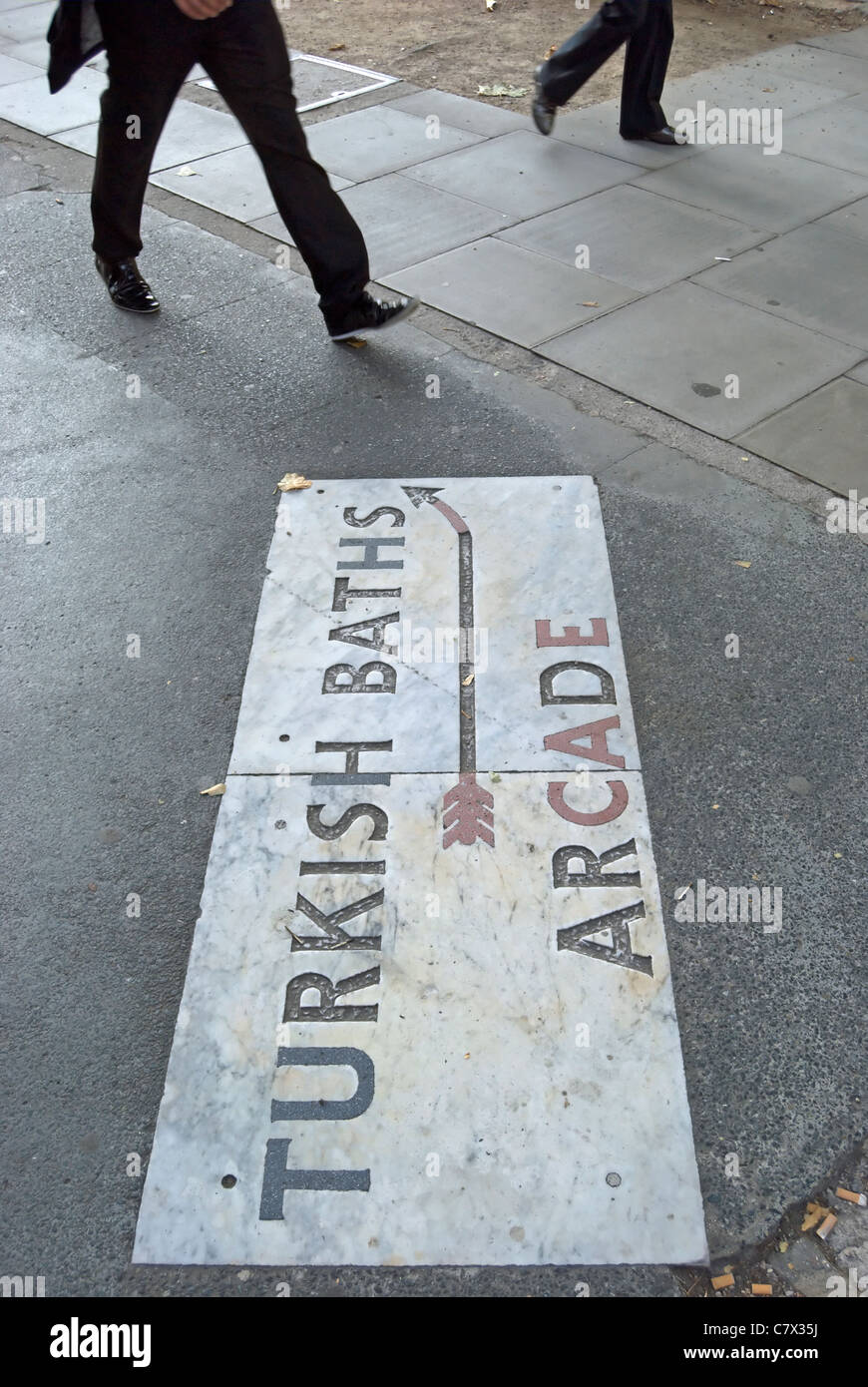 Pflaster-Zeichen für türkische Bäder arcade, Russell Square in London, England, mit zwei Passanten Stockfoto