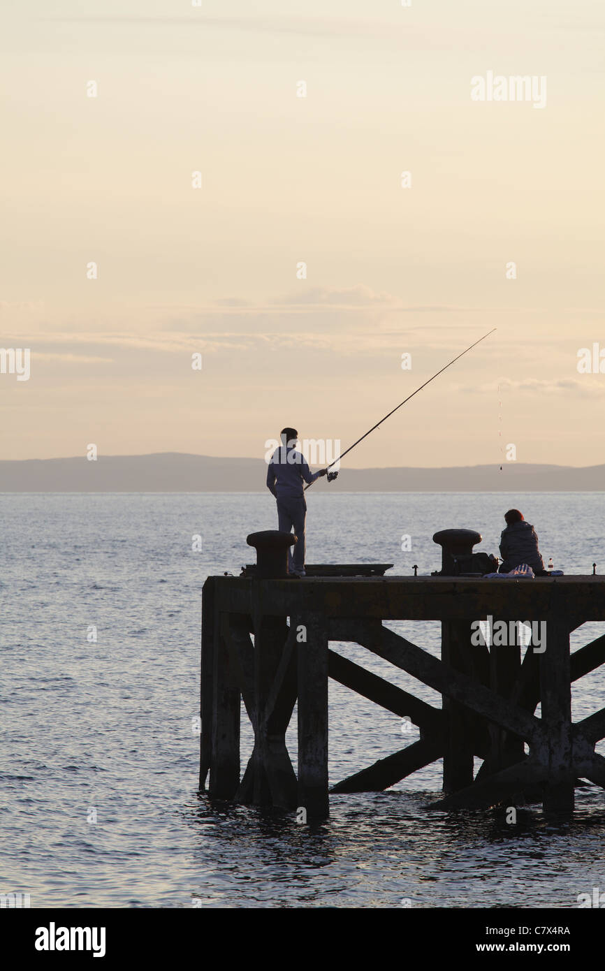 Angeln im Firth of Clyde am Portencross Pier bei Sonnenuntergang, North Ayrshire, Schottland, Großbritannien Stockfoto