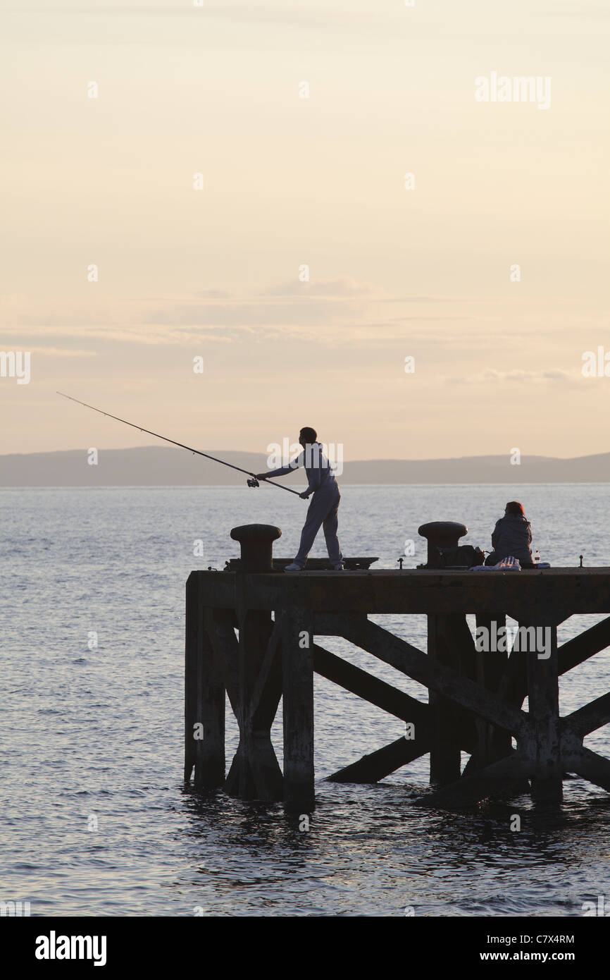 Angeln im Firth of Clyde am Portencross Pier bei Sonnenuntergang, North Ayrshire, Schottland, Großbritannien Stockfoto