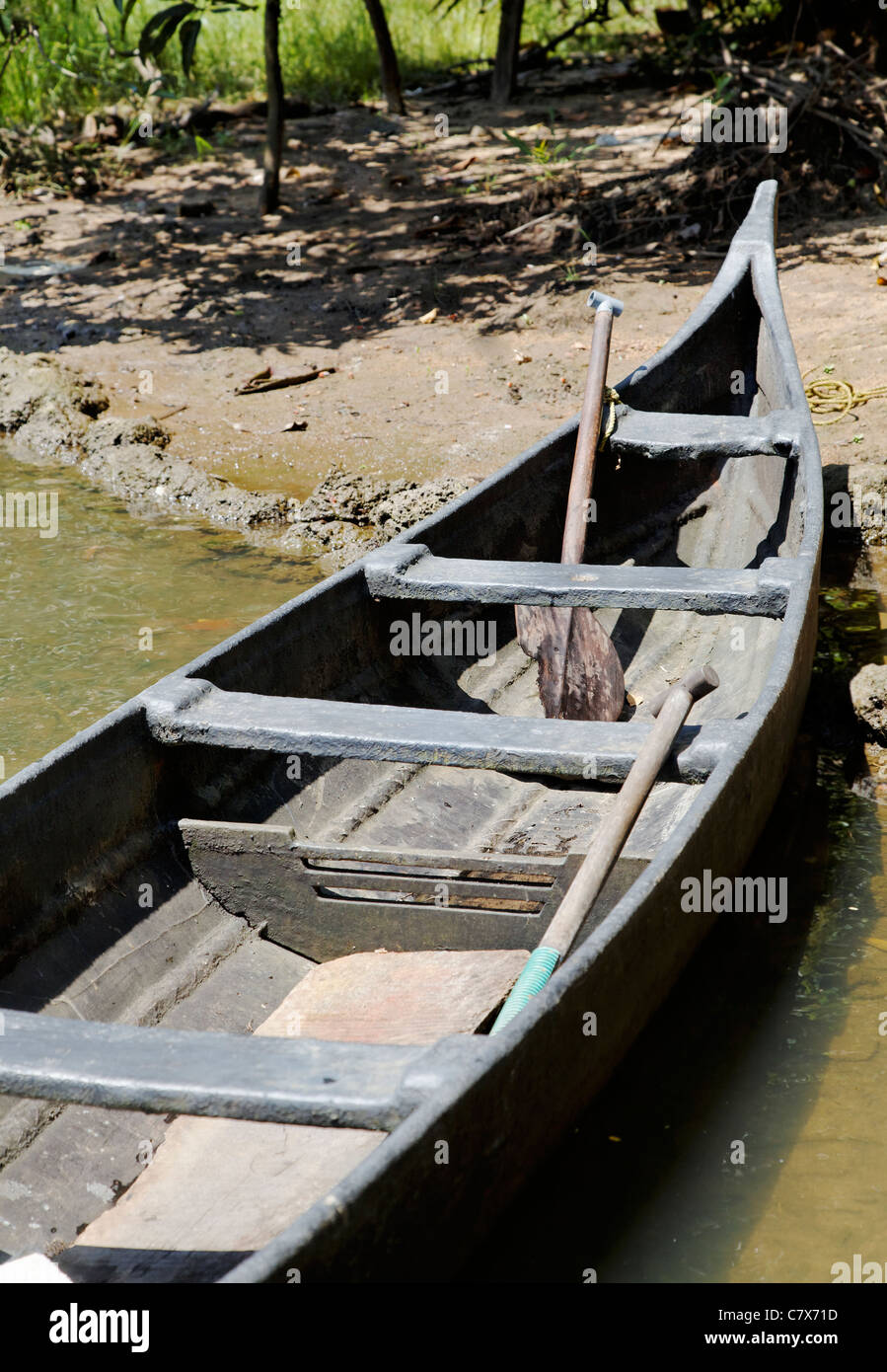 Portrait von vertäuten aus Holz schwarz Kanu am Ufer des Kerala Backwaters, Indien, konzeptionellen, abstrakten, sandigen Bank, vertikal, Ernte spac Stockfoto