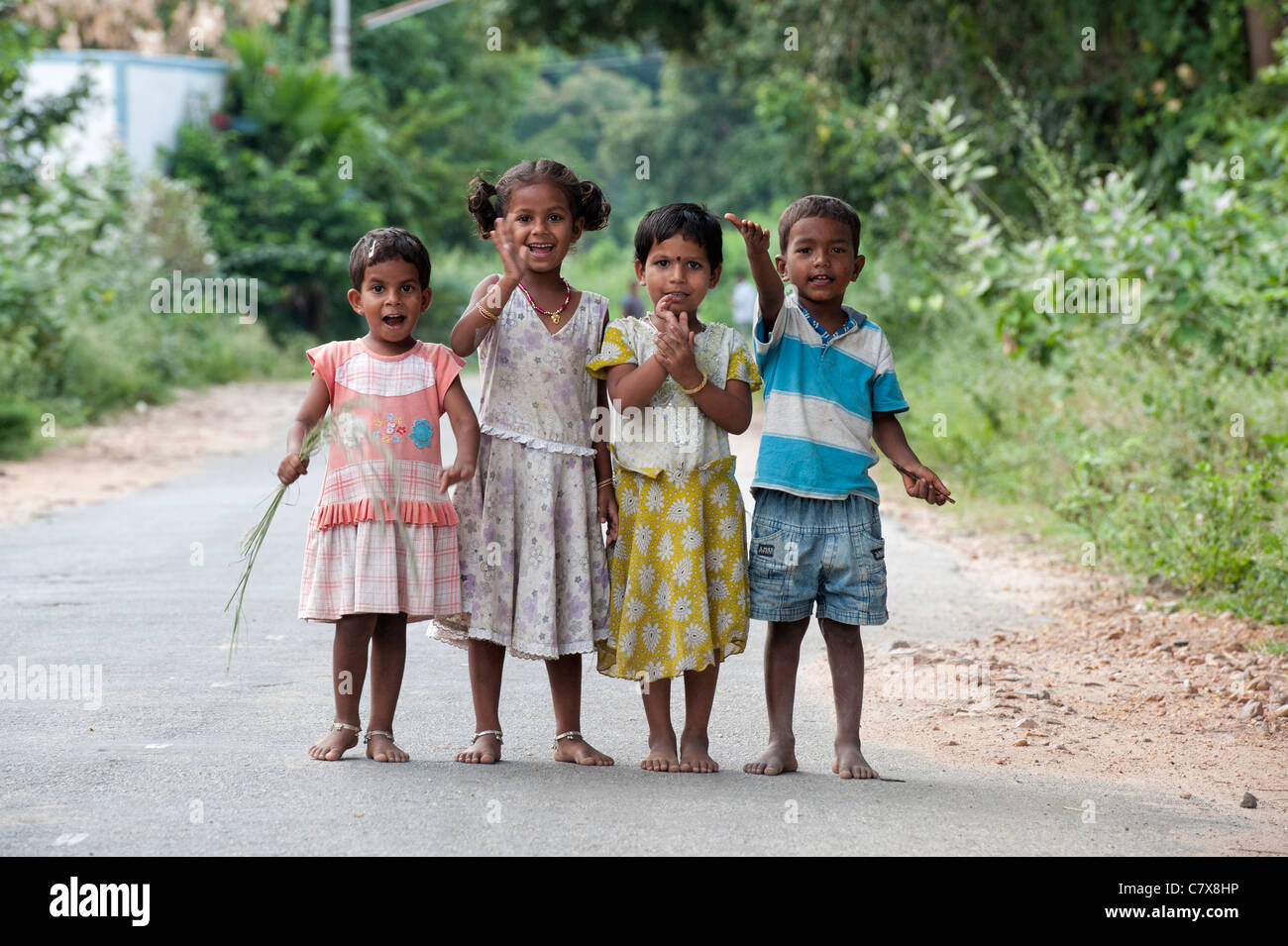 Glückliche junge indische Bauerndorf Kinder stehen auf einer Straße, lachen, winken und Lächeln auf den Lippen. Andhra Pradesh, Indien Stockfoto