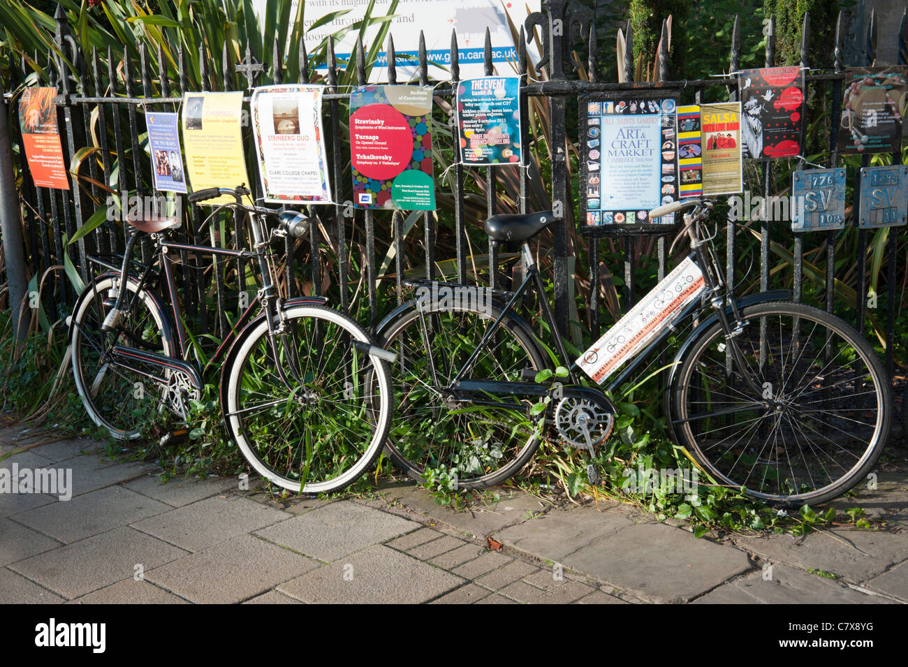 Zyklen, angekettet an Eisengitter in Cambridge Cambridgeshire England UK mit Plakaten an die Reling Werbeveranstaltungen befestigt. Stockfoto