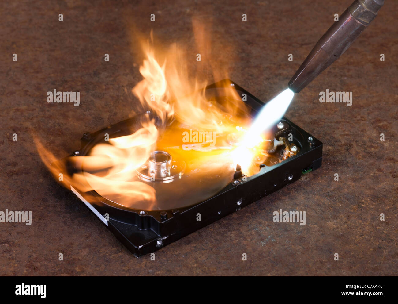 Brennen Sie eine Festplatte mit einem Schweißbrenner in rostigen Hintergrund Stockfoto