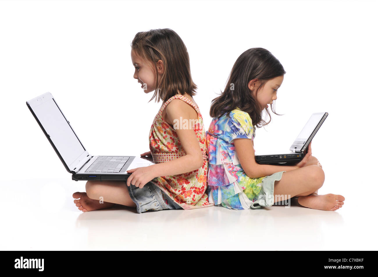 Zwei kleine Mädchen mit Laptop-Computern auf einem weißen Hintergrund isoliert Stockfoto