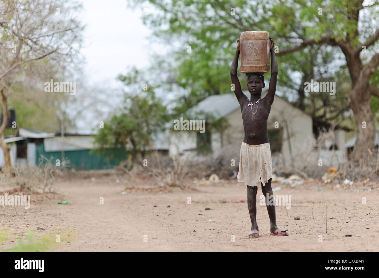 Ein junges Mädchen mit einem Wasserbehälter wieder aus dem Bohrloch, Luonyaker, Bahr El Ghazal, Süd-Sudan. Stockfoto