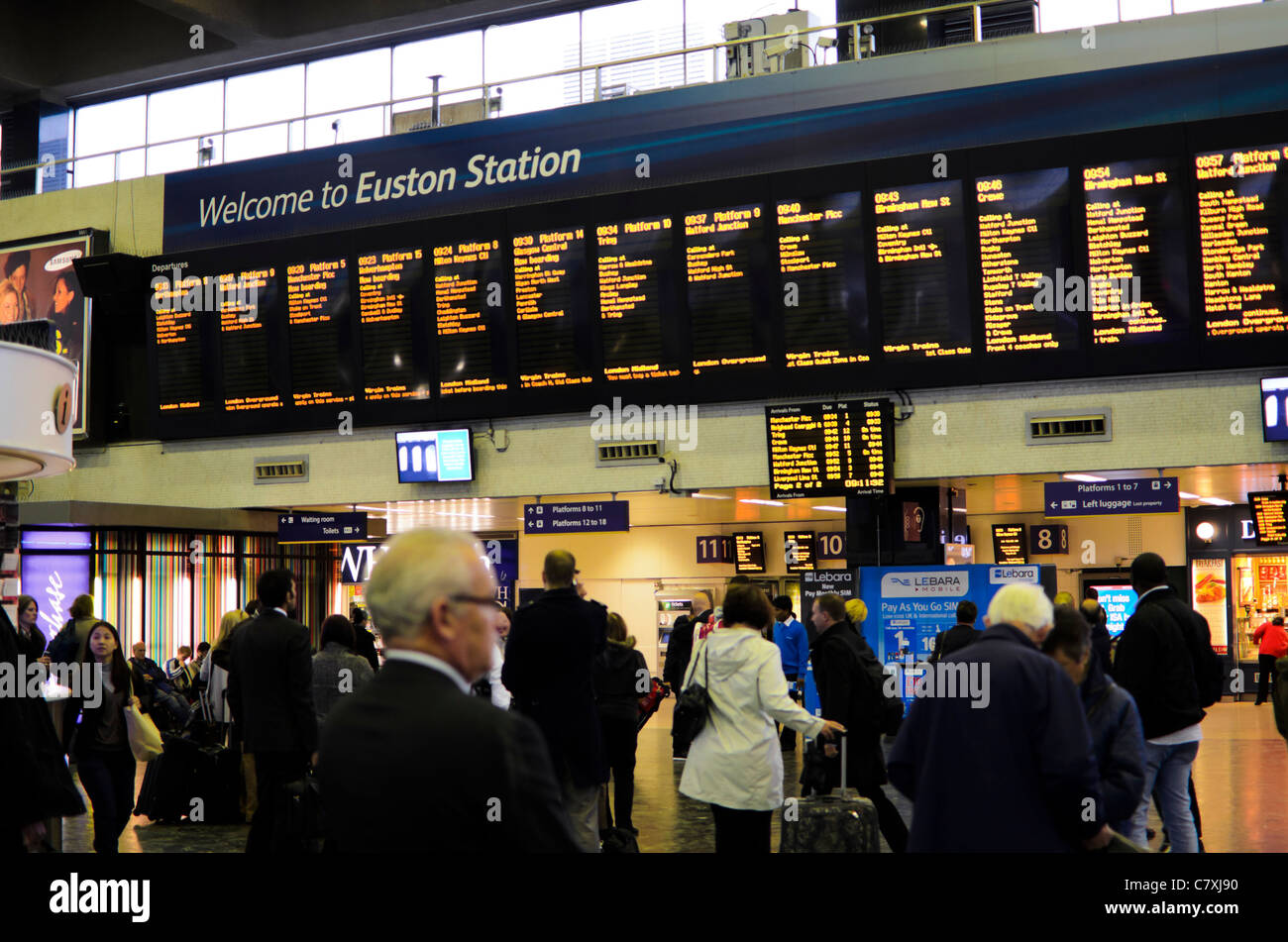 Passagiere einchecken Abfahrtszeiten in der Bahnhofshalle von Euston Station, London, England. Stockfoto