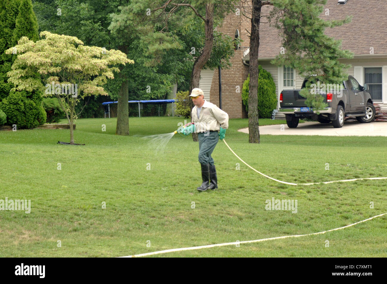 Professional Rasen Pflege Wartung Mann Sprays Unkraut und ernähren sich von einem Kunden Rasen. Stockfoto