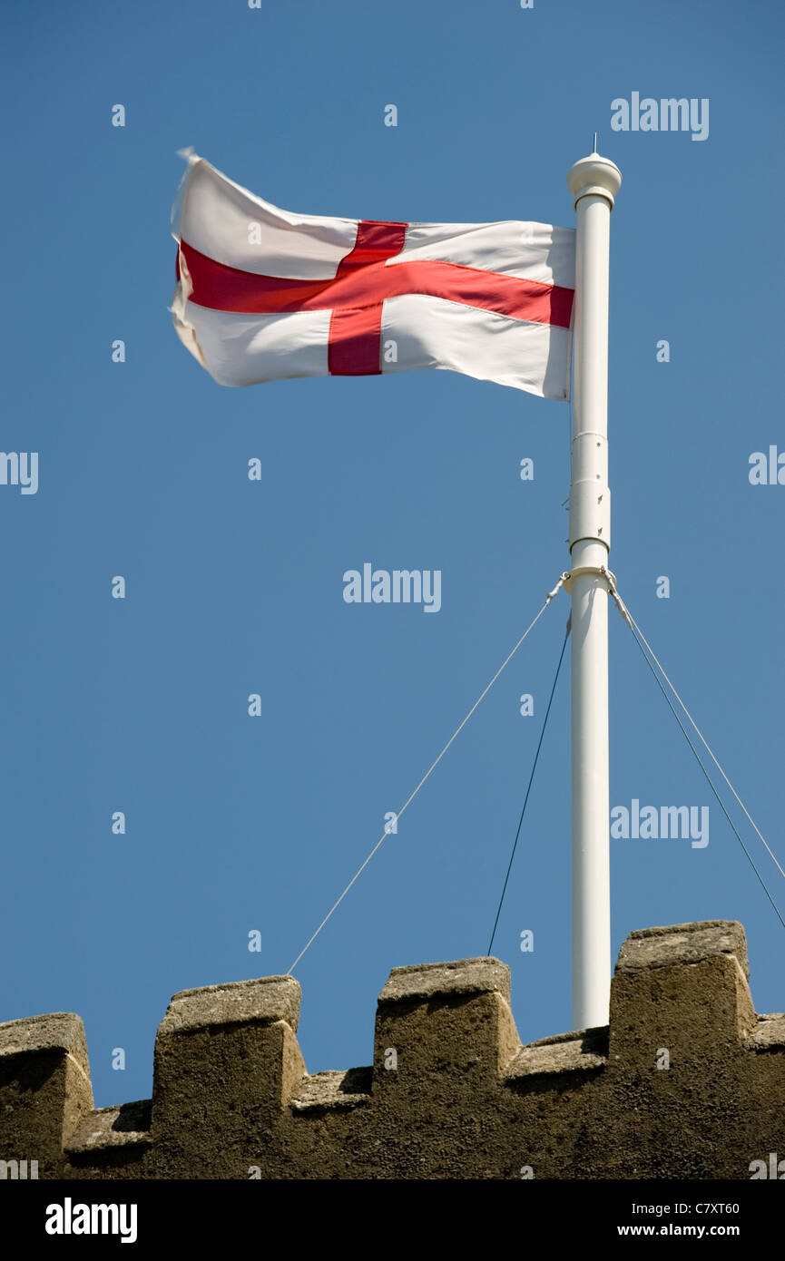 Das Kreuz von St. George Flag fliegt von einem kirchlichen Fahnenmast vor blauem Himmel. Stockfoto