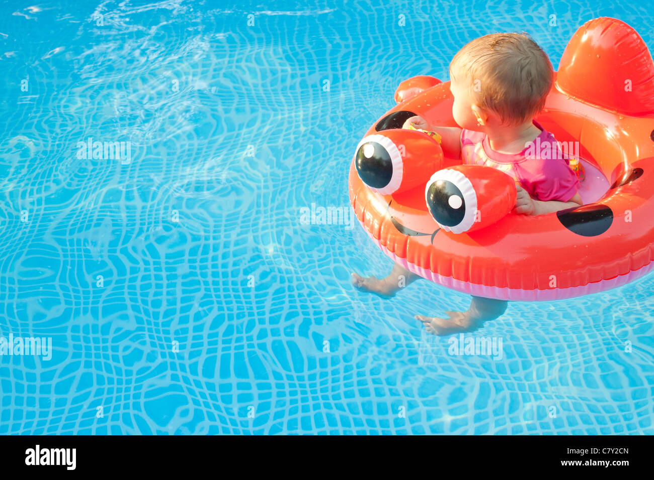 Kleines Kind im Floating Gerät wegsehen schwebt in einem Pool allein Stockfoto