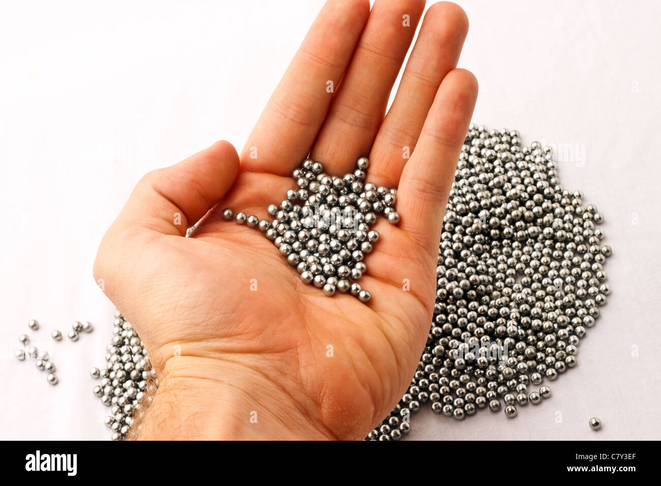 BB-Pellets in der Hand über Haufen von Silber pellets Stockfoto