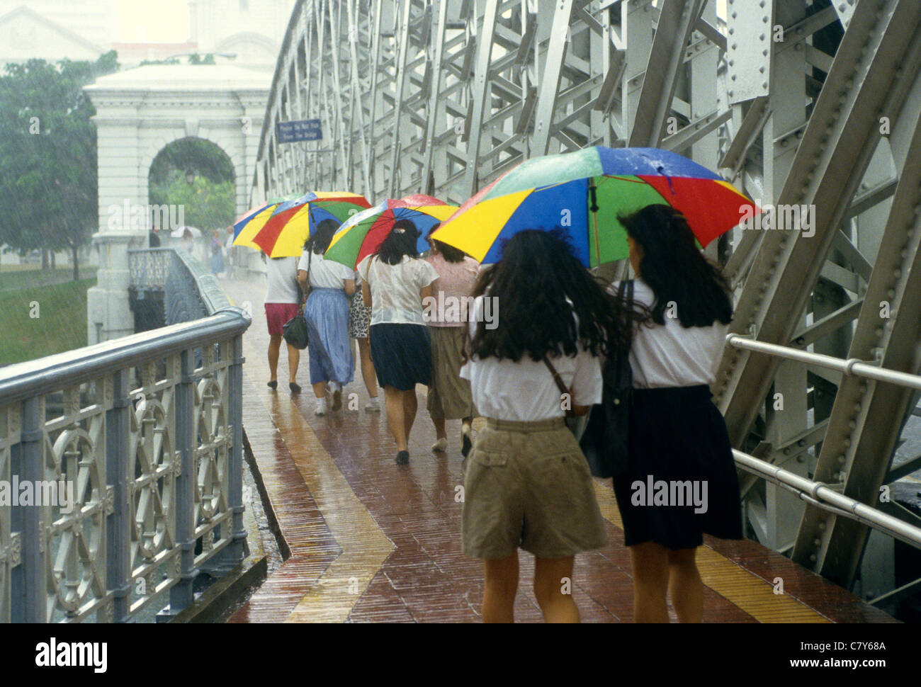 Junge Frauen mit Sonnenschirmen auf Cavanagh Bridge Singapur Stockfoto