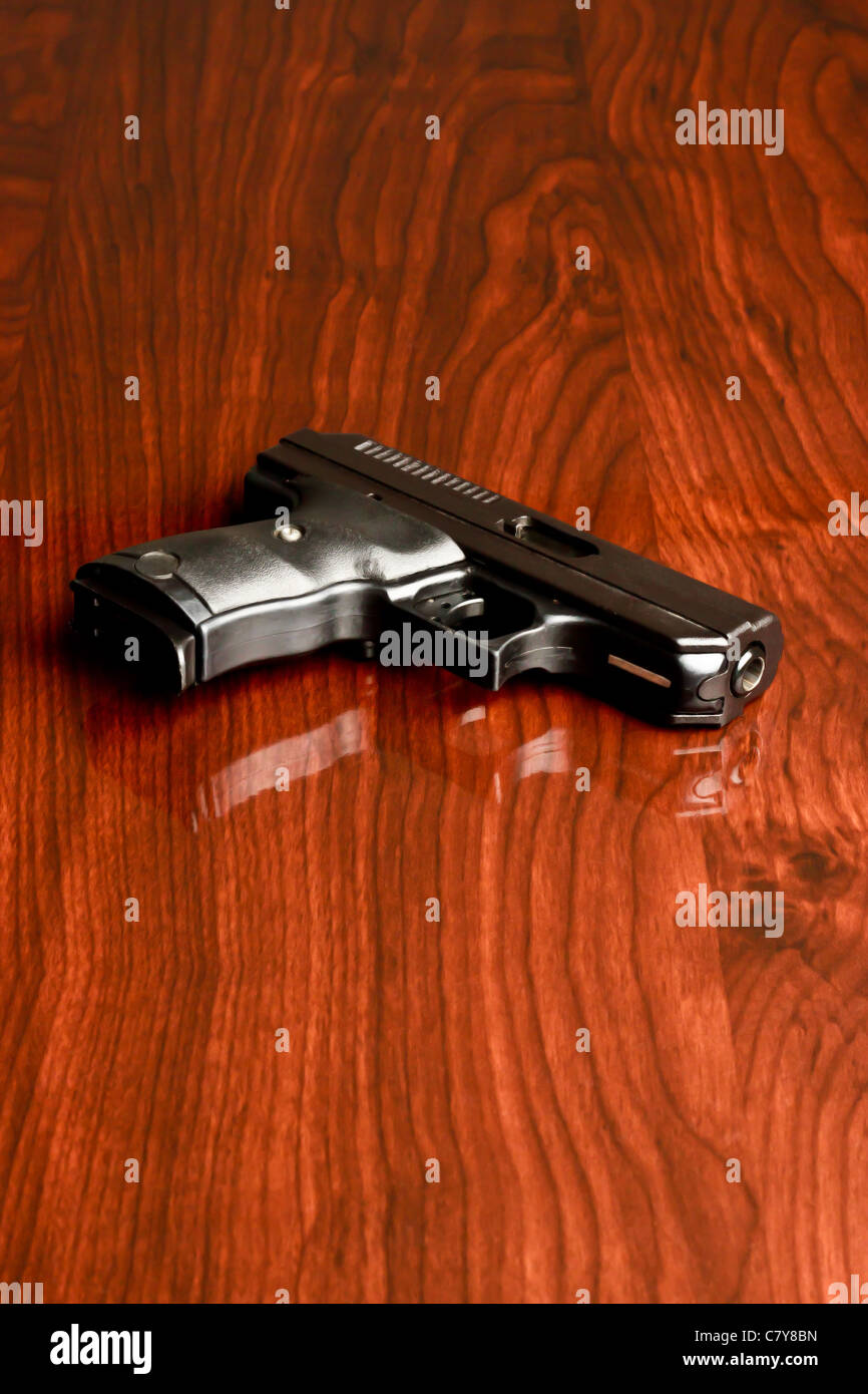 Neun Millimeter Pistole Verlegung auf einer reflektierenden Oberfläche aus Holz Stockfoto
