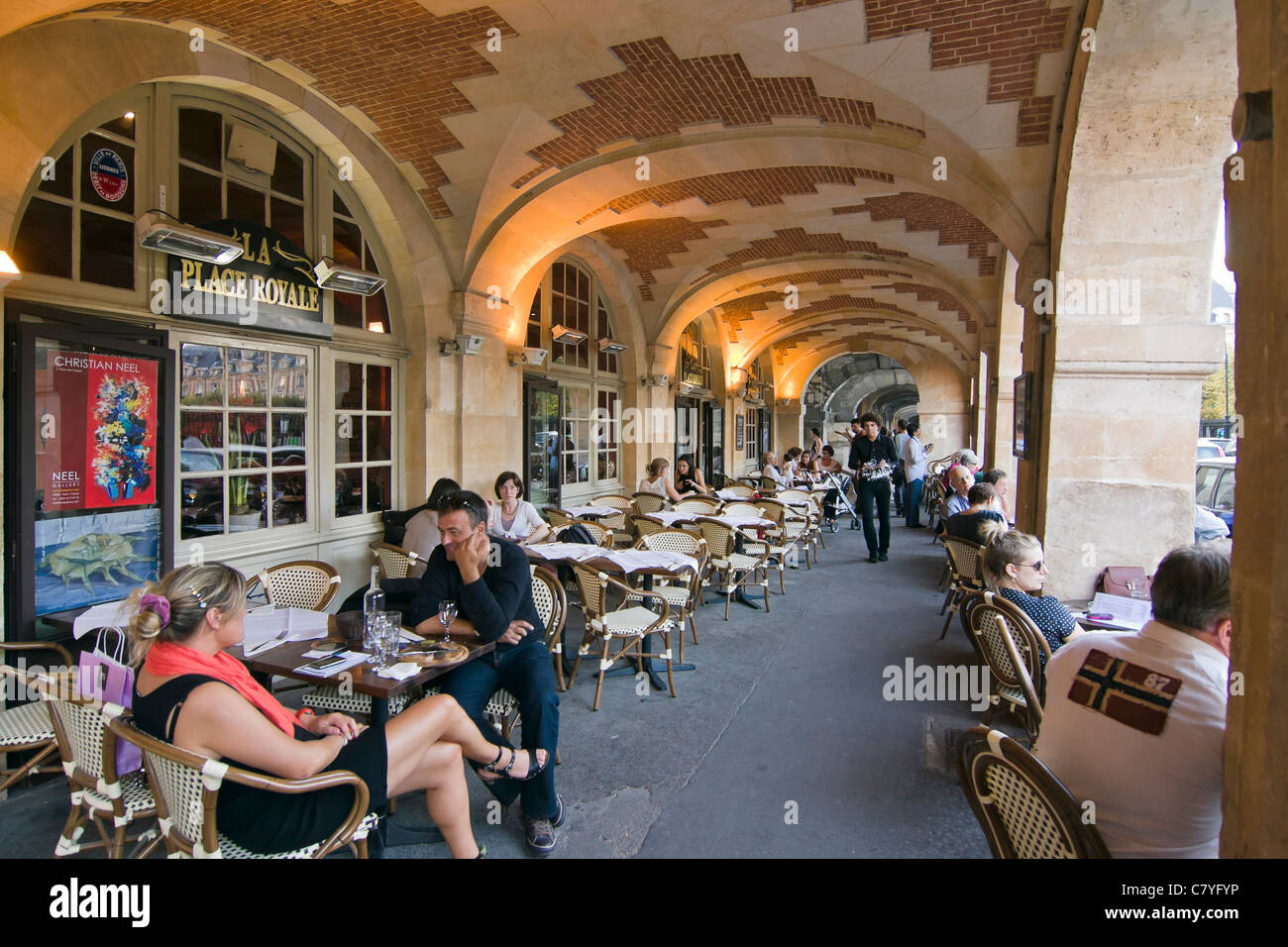 Menschen, die genießen eines Drink an einer Caféterrasse unter den Arkaden der Place des Vosges - Paris, Frankreich Stockfoto