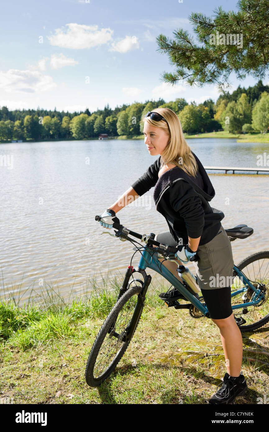 Schöne junge blonde Frau Reiten Fahrrad See Sommertag