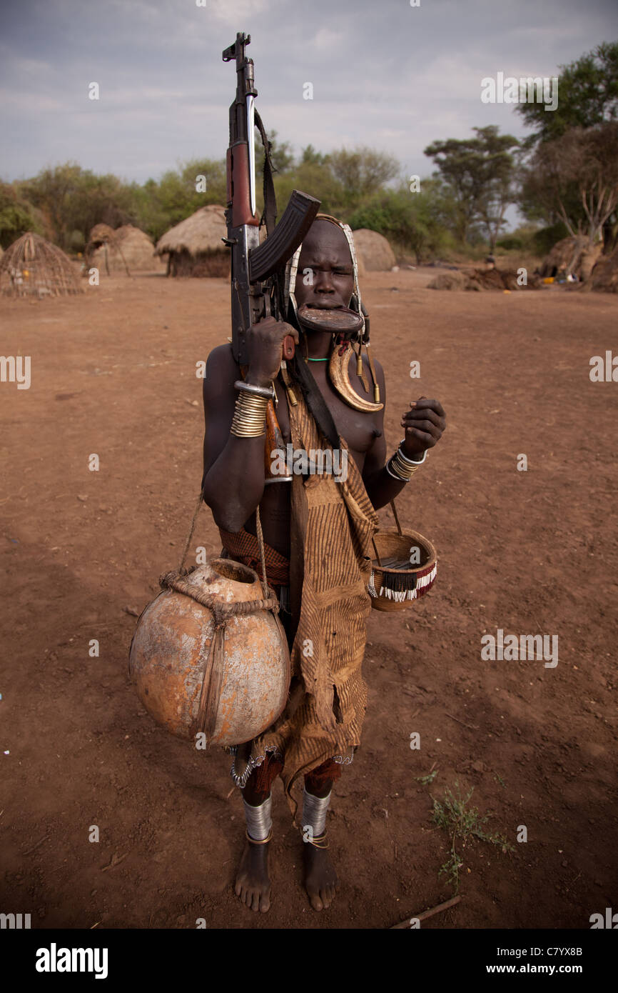 Mursi-Frau mit Lippe Datenträger und AK47, Jinka, Omo-Tal in Äthiopien, Afrika Stockfoto