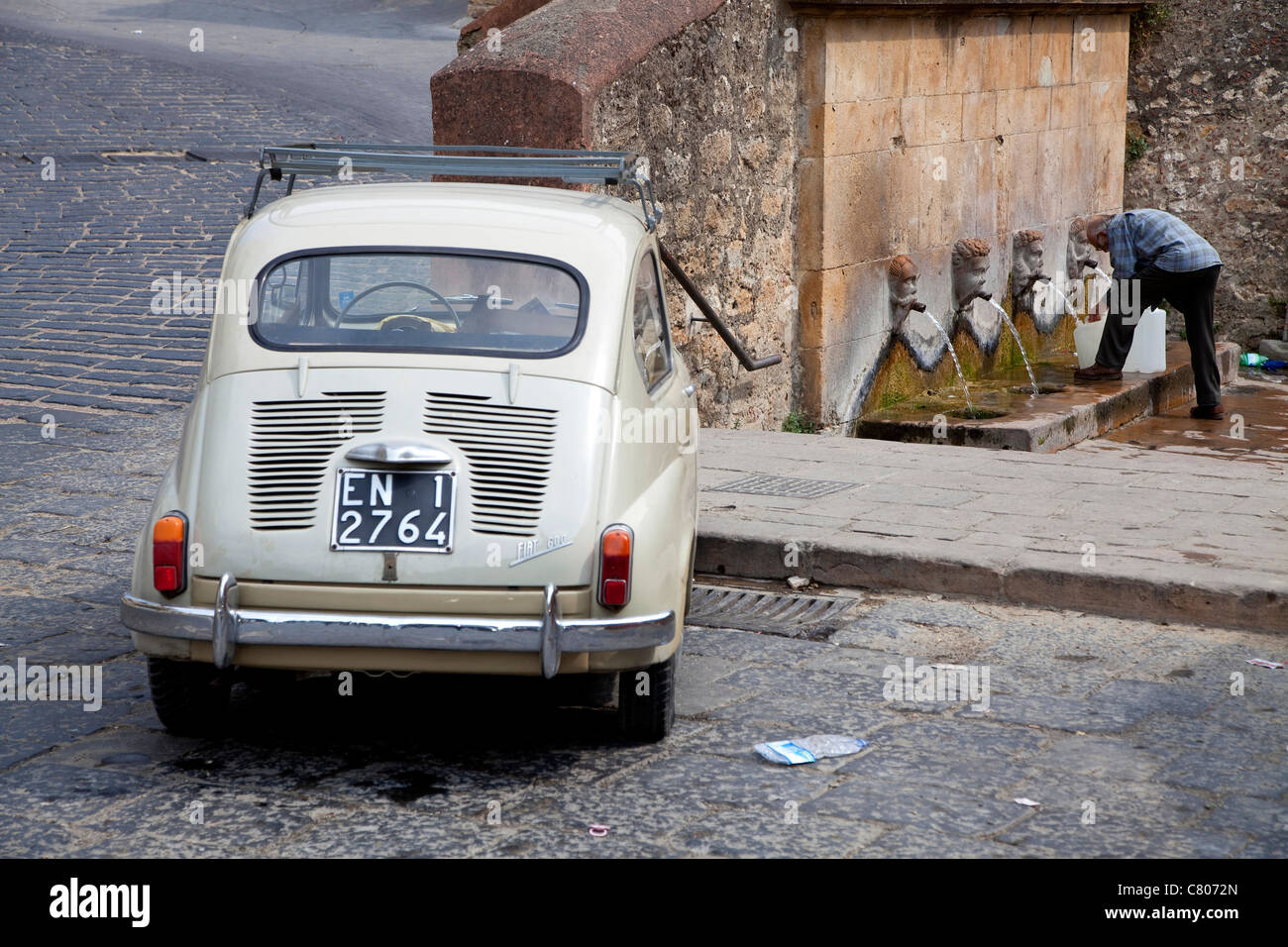 Alten Fiat 600 Auto und Mann mit Wassertanks an Brunnen, Piazza Armerina, Sizilien, Sicilia, Italien Stockfoto