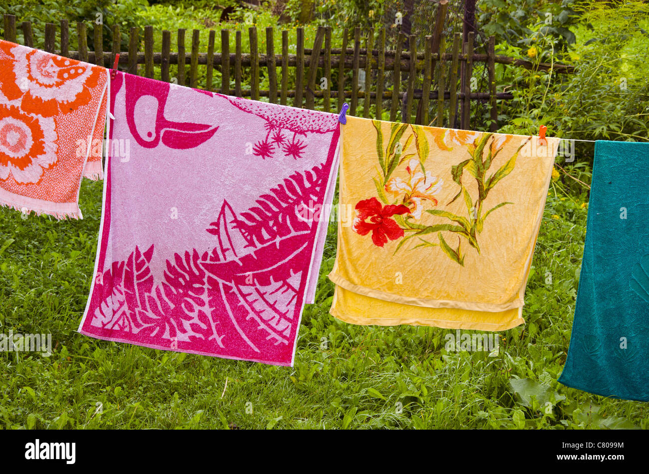 Multicolor Handtücher hängen Zeichenfolge im Gehöft. Holzzaun im Hintergrund. Stockfoto