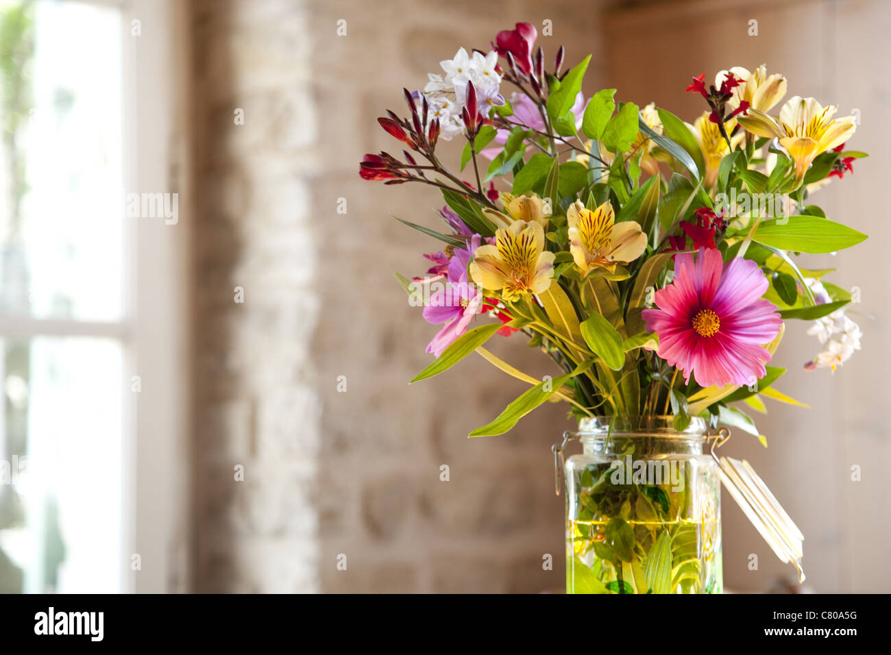 Farbfoto von einem frischen Blumenstrauß setzen innen auf dem Küchentisch an einem Frühlingsmorgen in Frankreich. Stockfoto