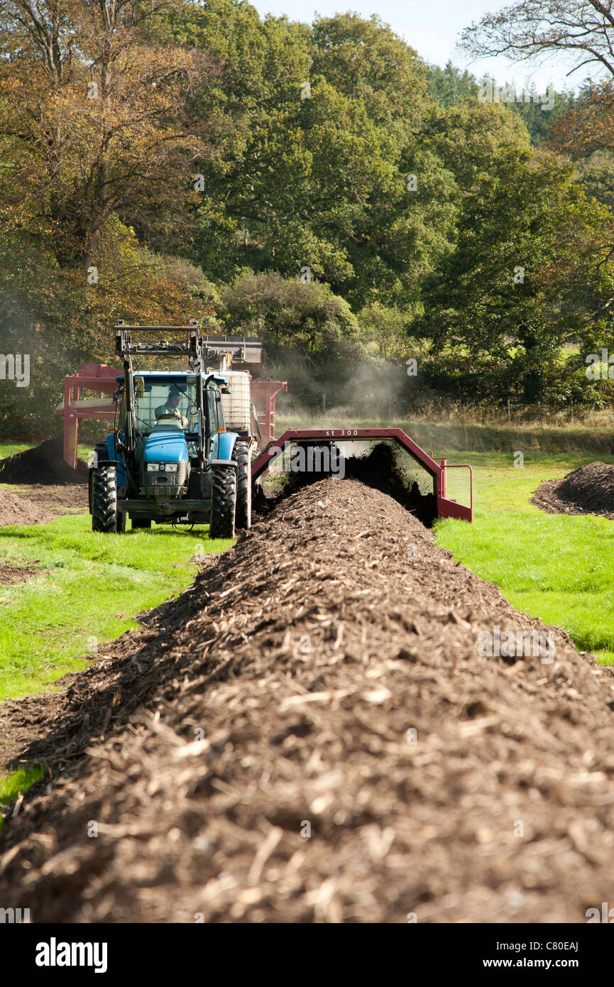 Groß angelegte Kompostierung heimischen grünen Hausmüll, UK - Traktor umdrehen das Material zur Beschleunigung der Kompost-Herstellung Stockfoto