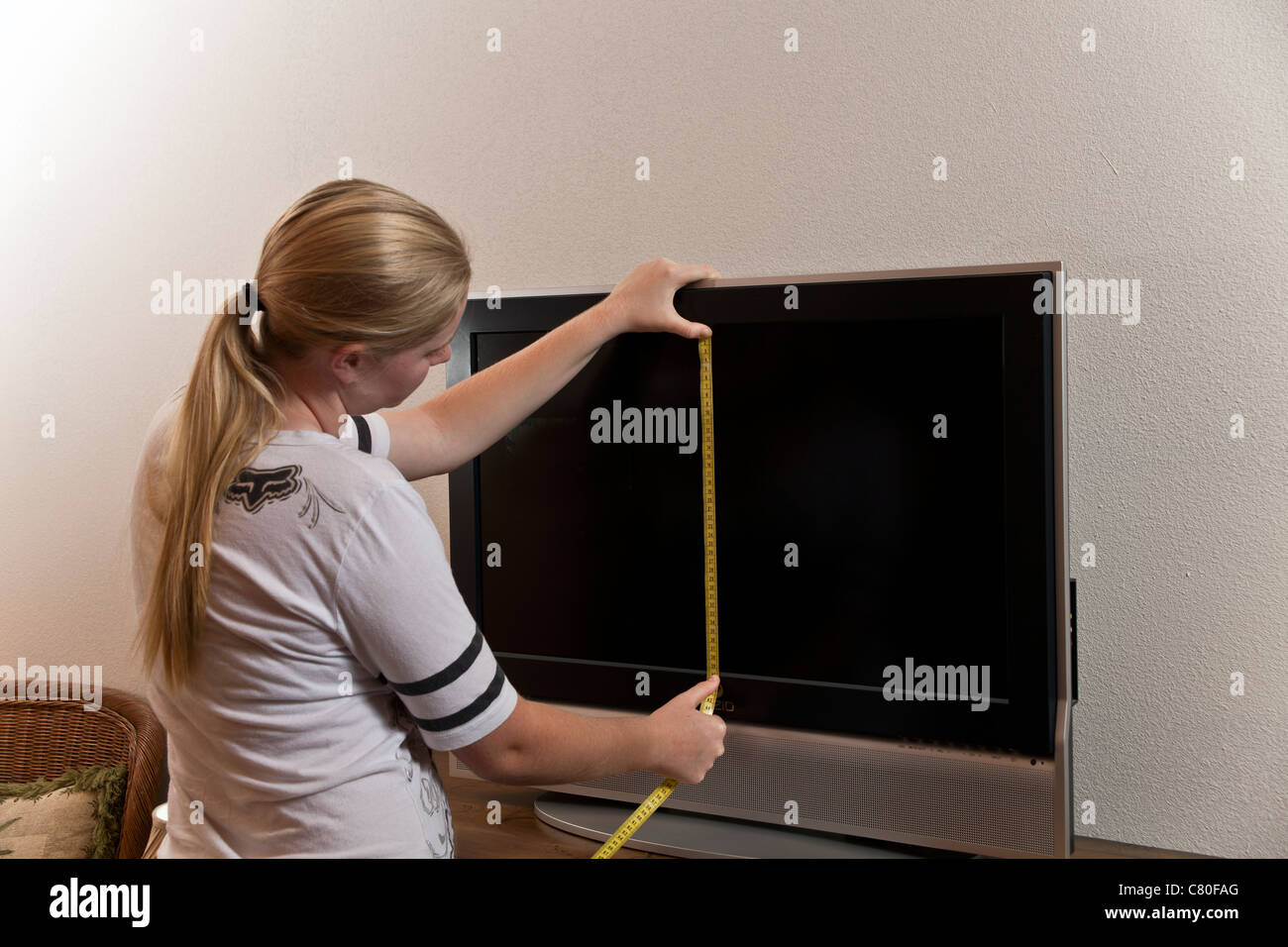 Teenager-Mädchen misst die Maße von einem 80-Zentimeter-Bildschirm. Herr © Myrleen Pearson Stockfoto