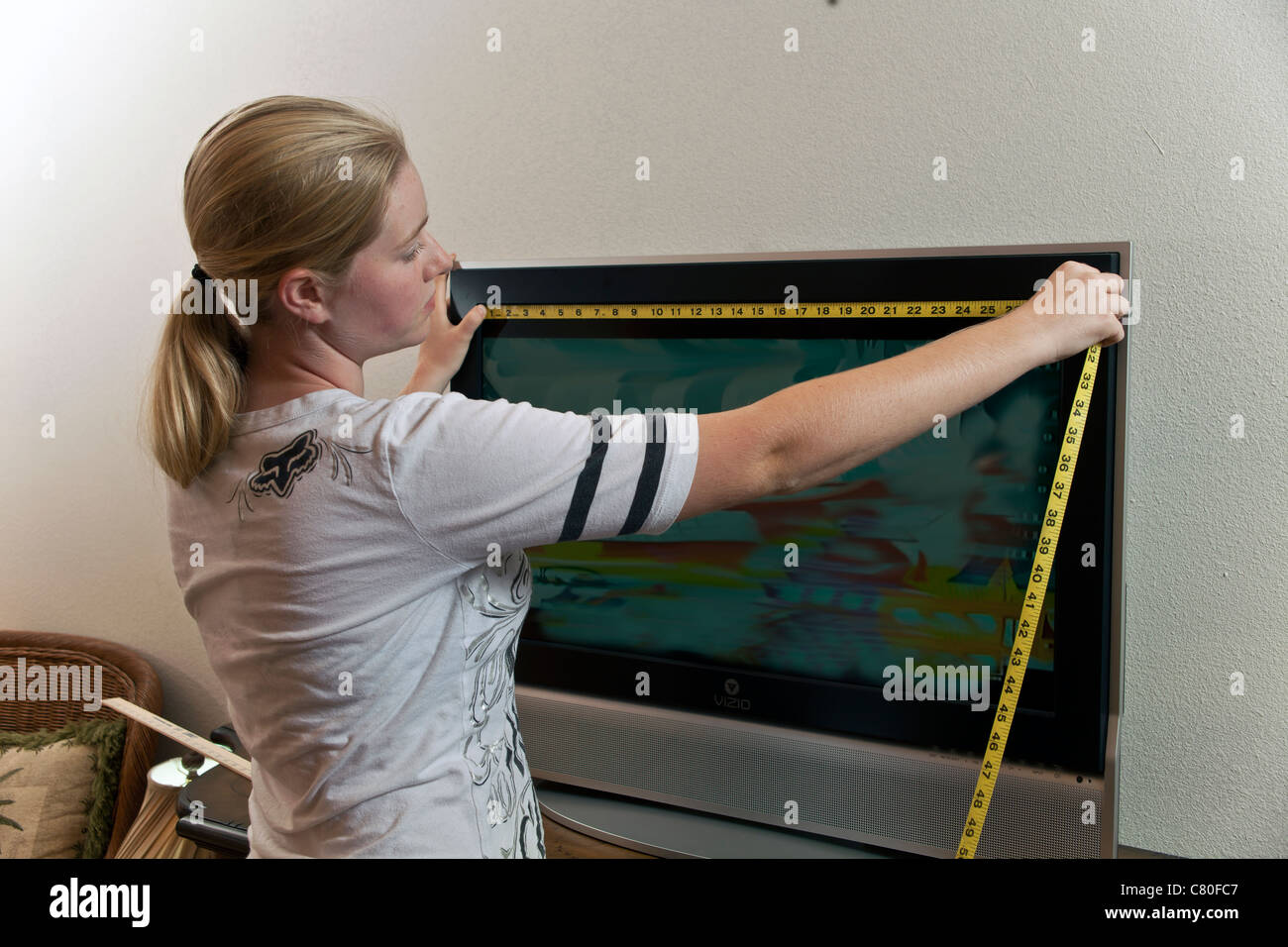 Teenager-Mädchen misst die Maße von einem 32-Zoll-TV-Bildschirm. Herr © Myrleen Pearson Stockfoto