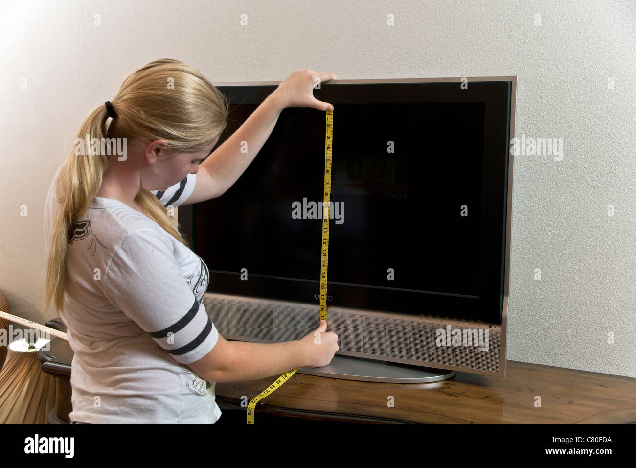 Teenager-Mädchen misst die Maße von einem 32-Zoll-TV-Bildschirm. Herr © Myrleen Pearson Stockfoto