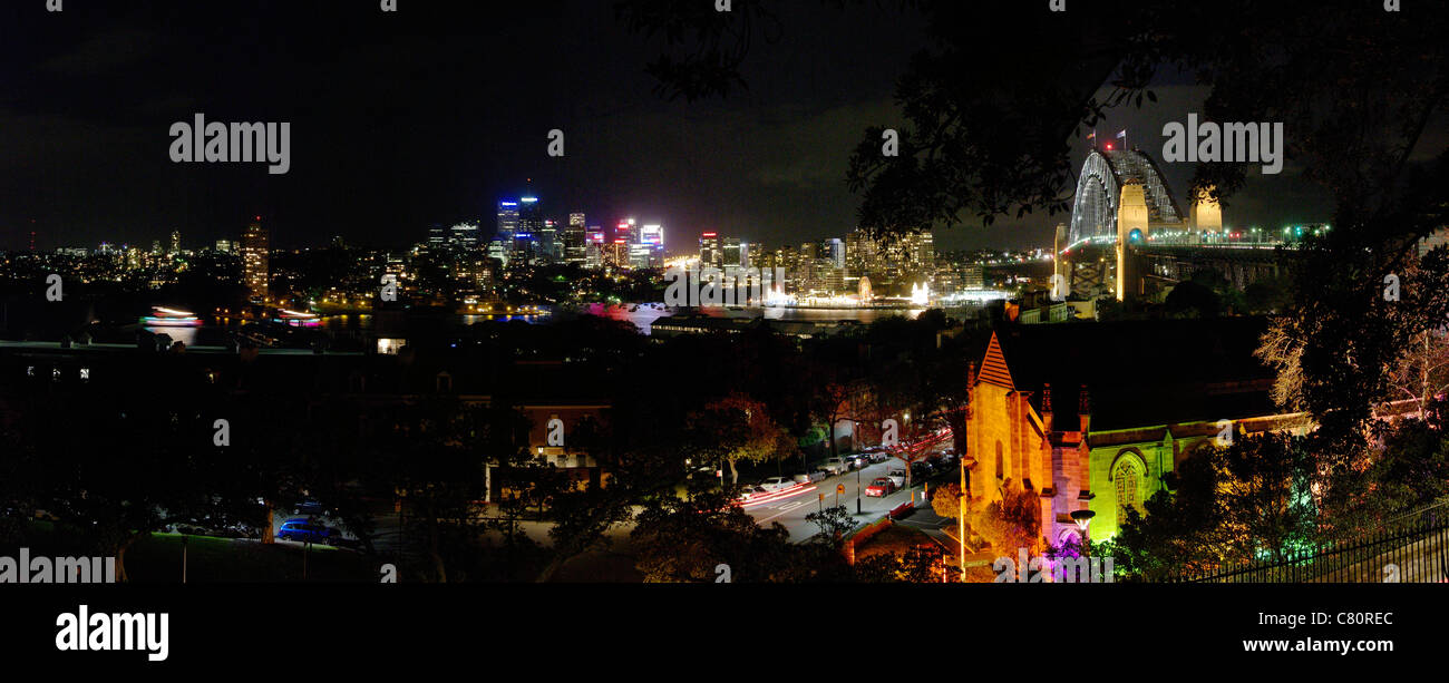 Nacht Zeit Panoramablick auf Sydney Skyline zeigt Hafenbrücke und historischen Gebiet der Felsen im Vordergrund. Alten Garnisonskirche Stockfoto