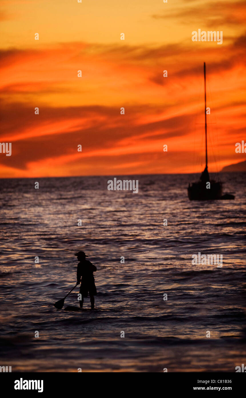 Silhouette von nicht identifizierbaren Stand up Paddel Boarder Köpfe, Segelboot bei Sonnenuntergang. Stockfoto