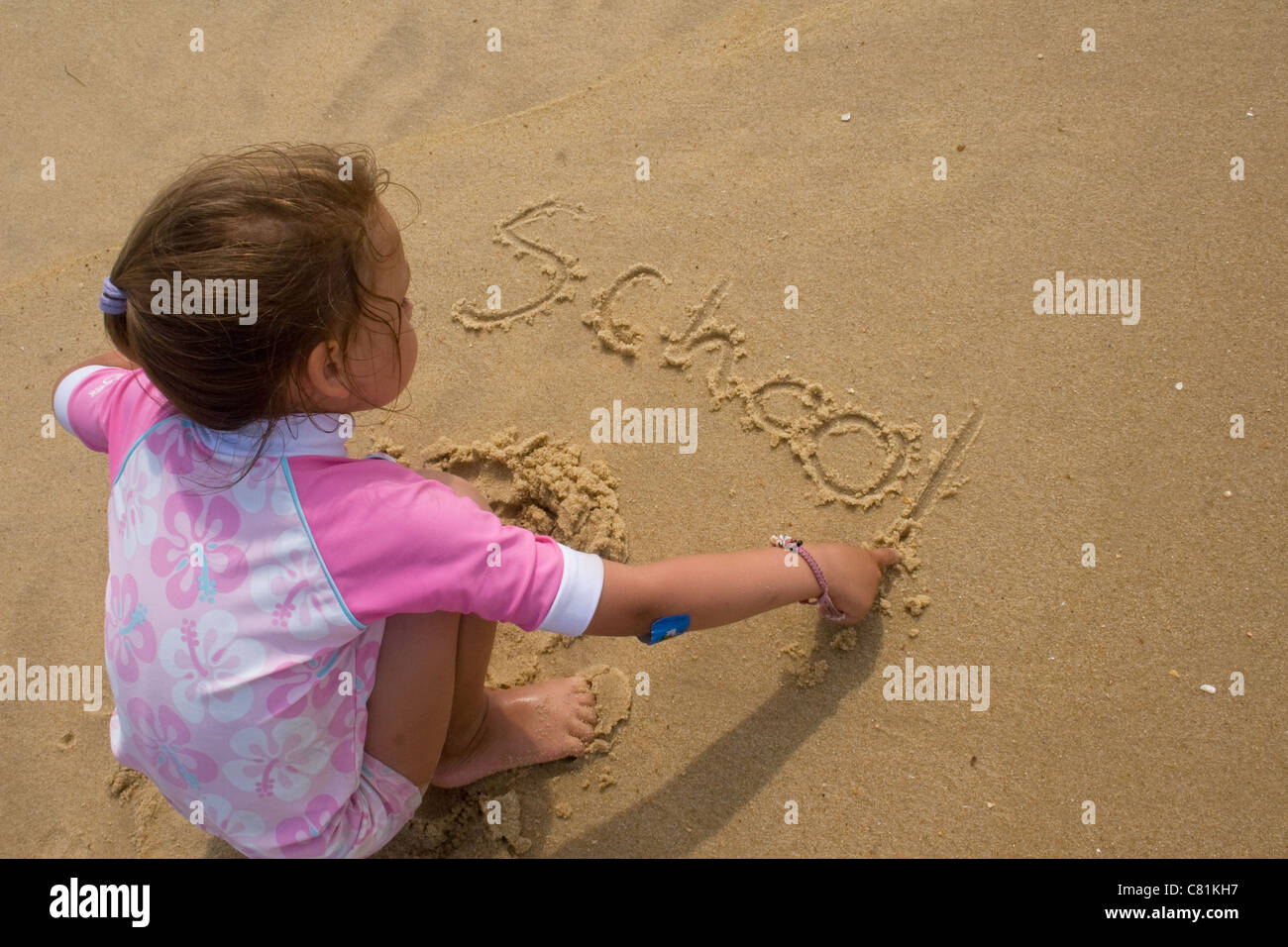 Junges Mädchen schreibt Schule im sand Stockfoto