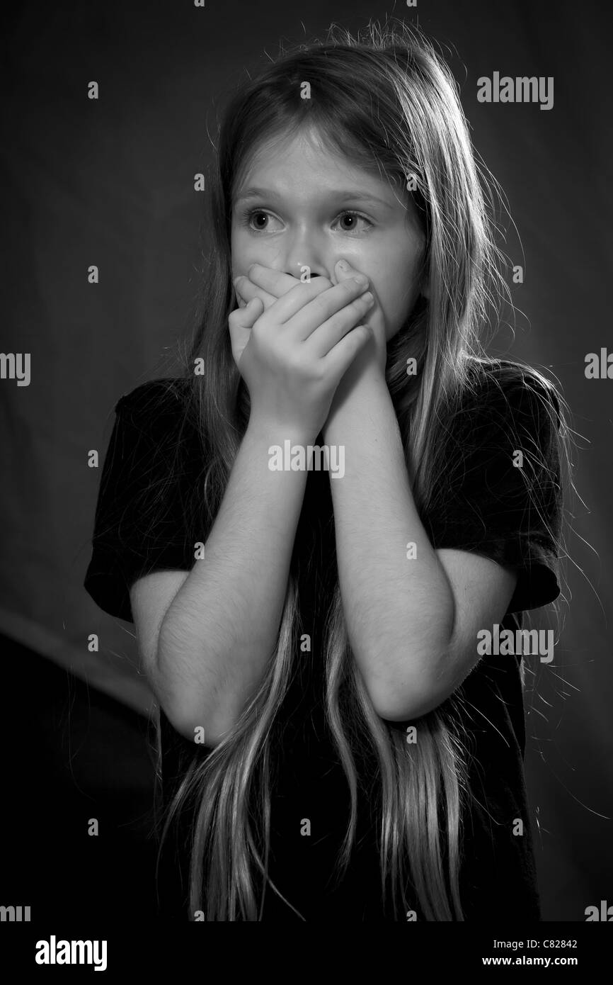acht Jahre altes Mädchen hält ihre Hände zum Mund, schockiert Stockfoto