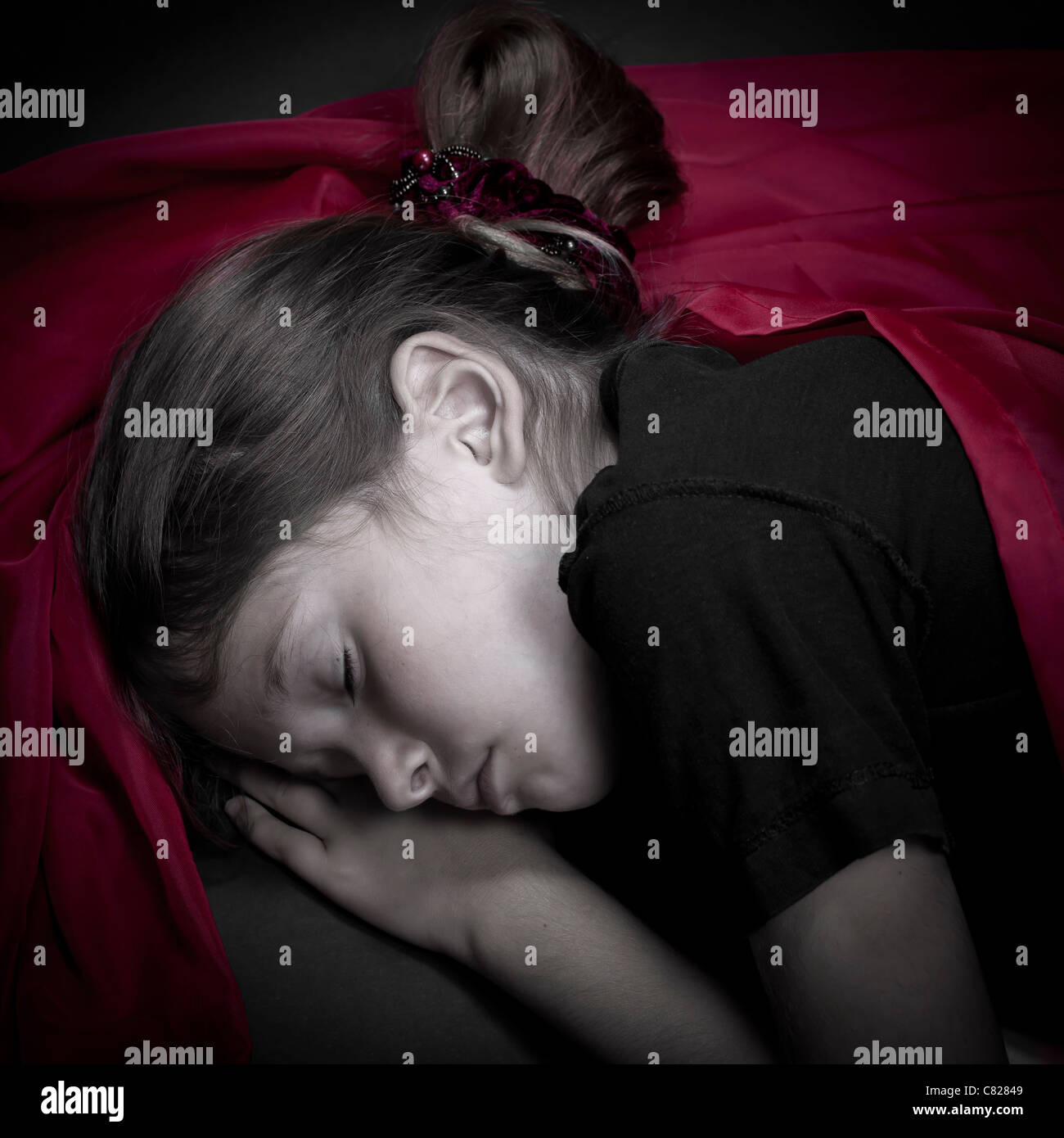 eine Mädchen ist in einem roten Tuch schlief zusammengerollt Stockfoto