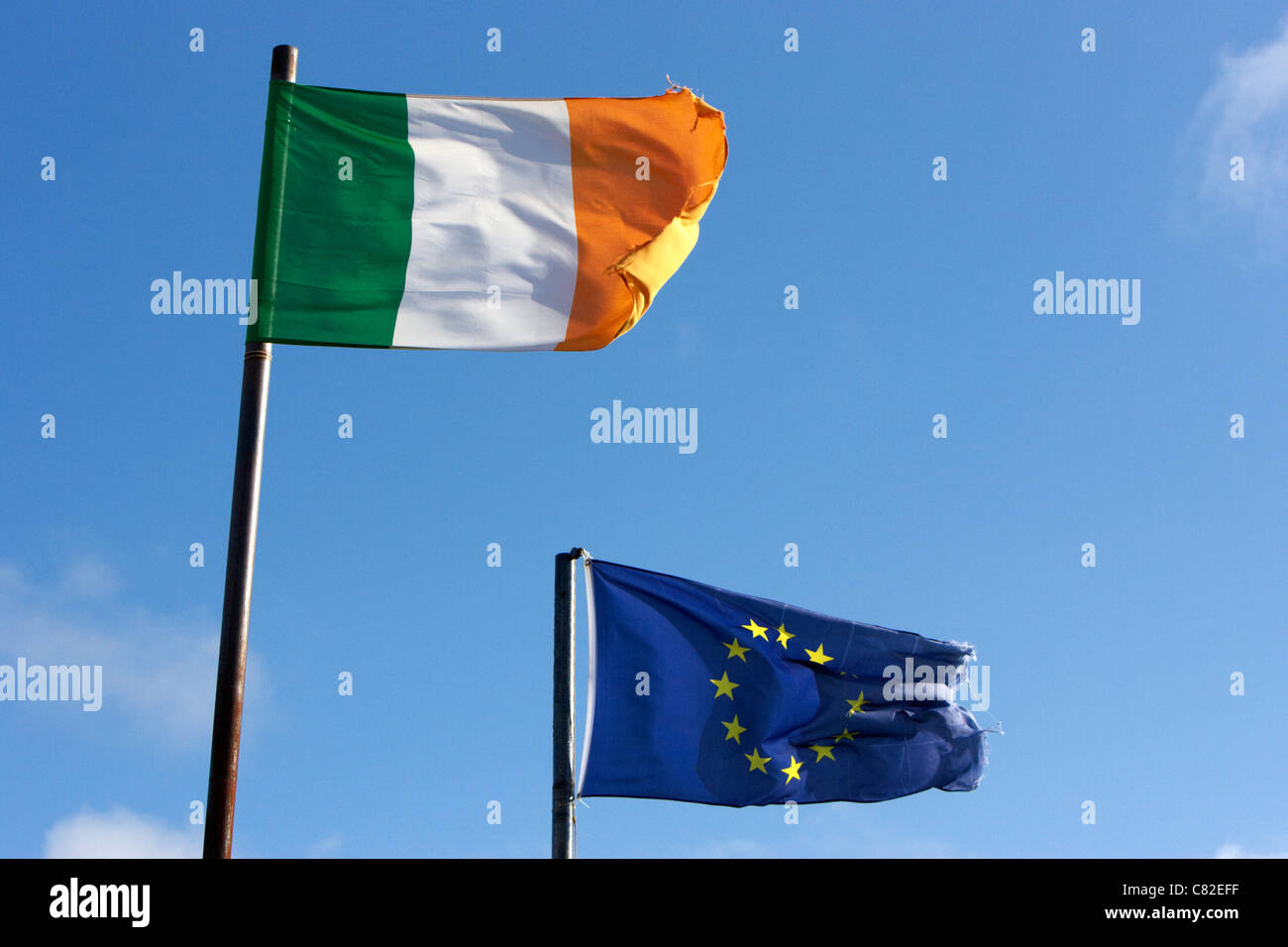 Nationale irische Trikolore und EU-Flaggen fliegen mit ausgefransten Rändern in der Republik Irland in der Nähe der Grenze zu Nordirland Stockfoto