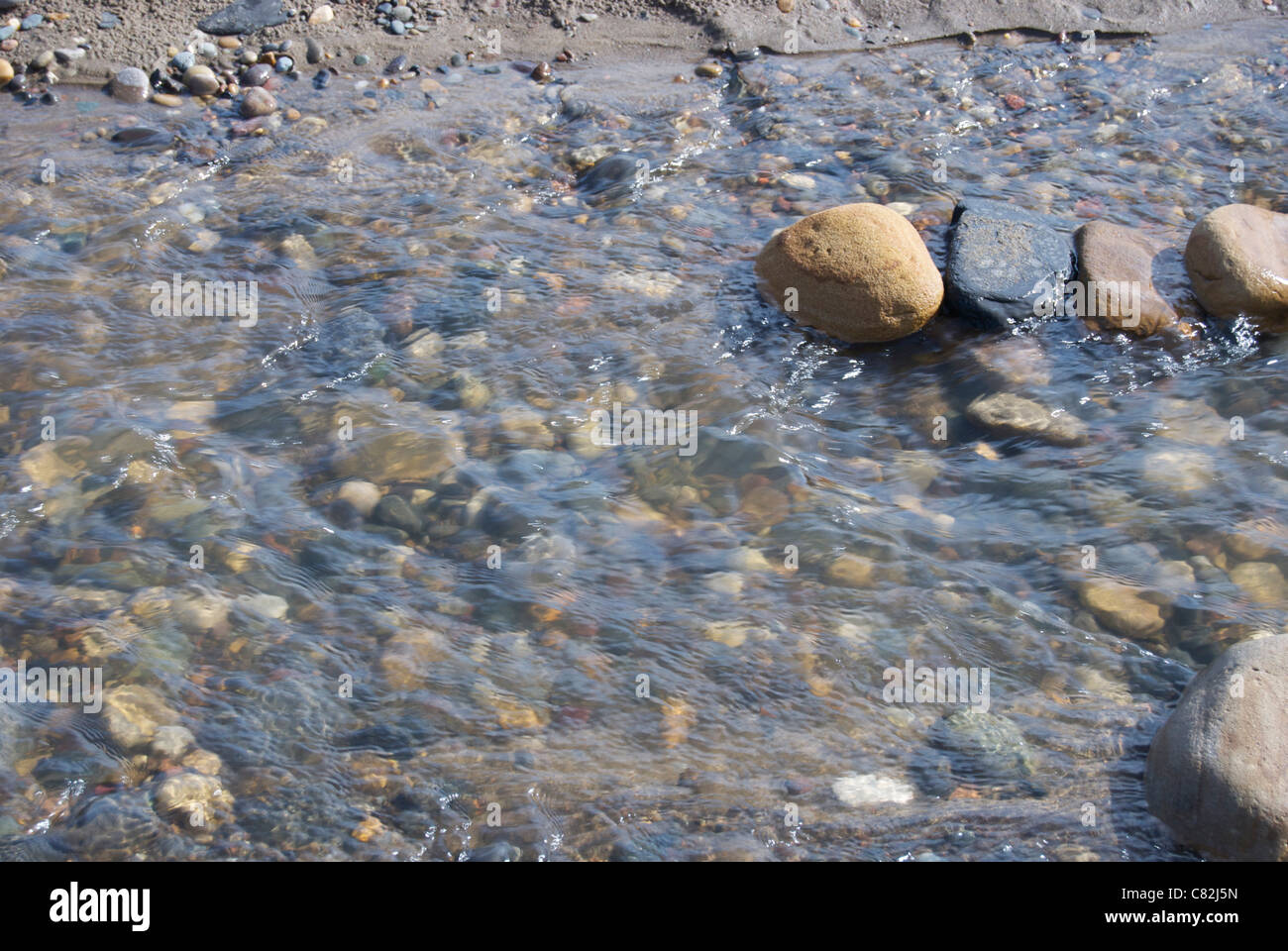 Wasser fließt über Sand und Kies Stockfoto