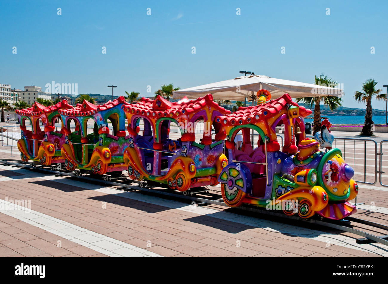 Ein bunter Zug und Trainer für Kinder Fahrten an der neuen Strandpromenade Entwicklung, Civitavecchia, Italien Stockfoto