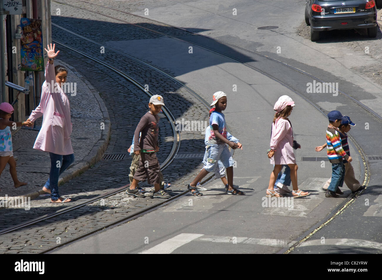 Kindergarten / Gästekindergarten Kinder überqueren die Straße und Straßenbahn Linien, Stadtteil Alfama, Lissabon, Portugal Stockfoto