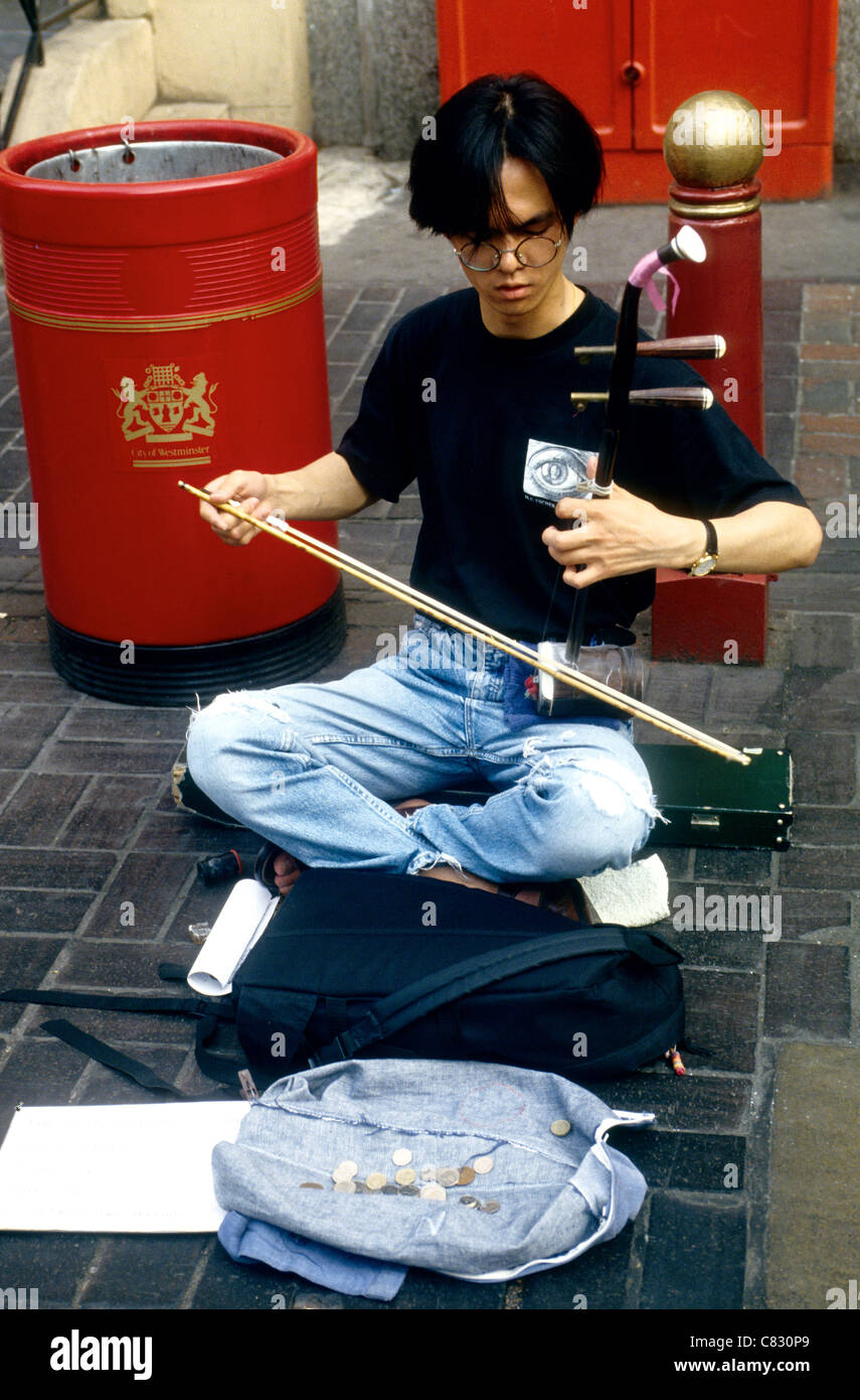 Eine klassische Musiciain spielt eine Geige eine Zeichenfolge in einer Londons Chinatown, Soho London .de Stockfoto
