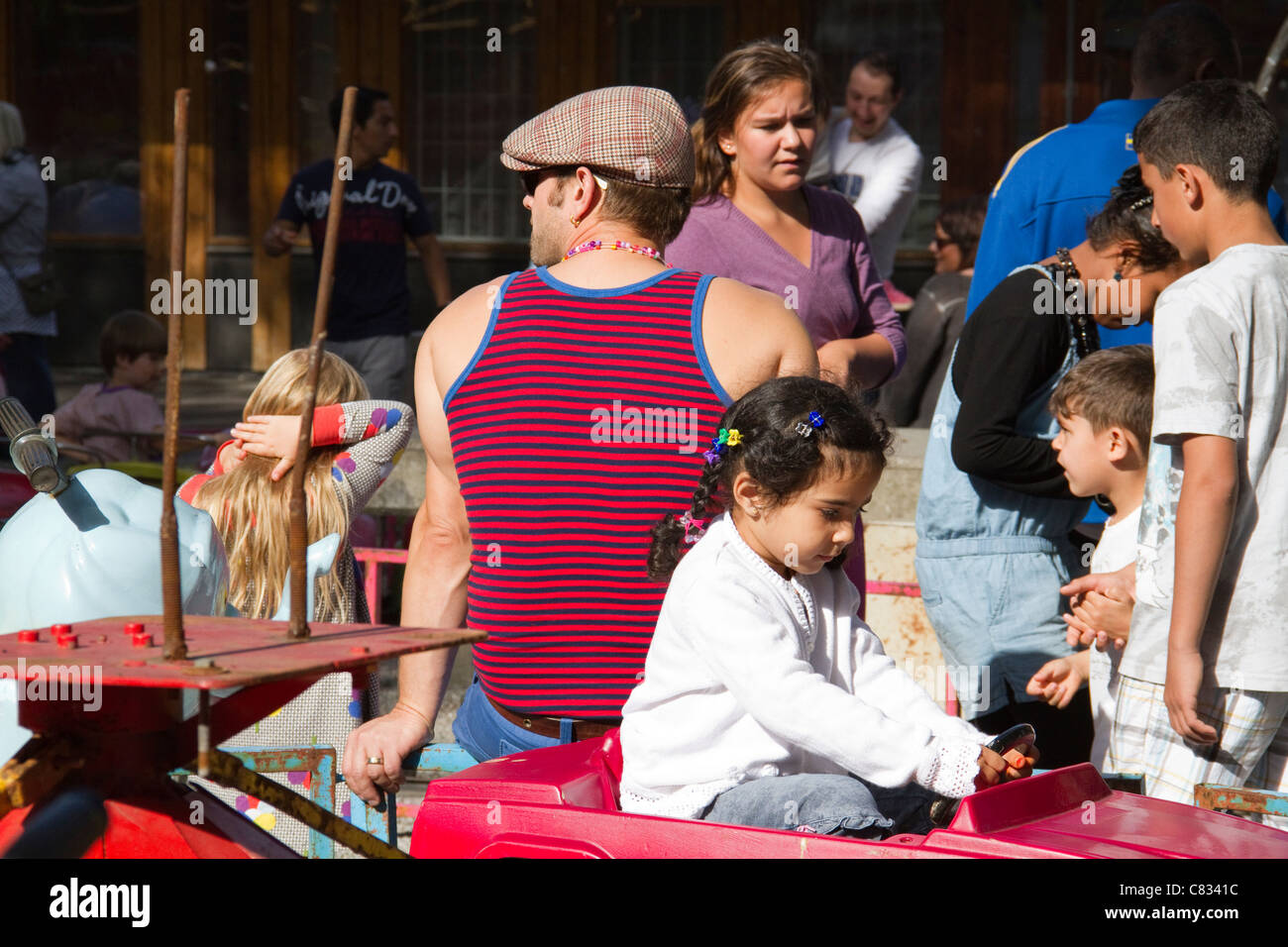 Mann in Kappe sitzt mit dem Rücken zur Kamera wie Menschen Eid Al-Fitr mit Mini-Messegelände in Tensta Stockholm Schweden feiern Stockfoto