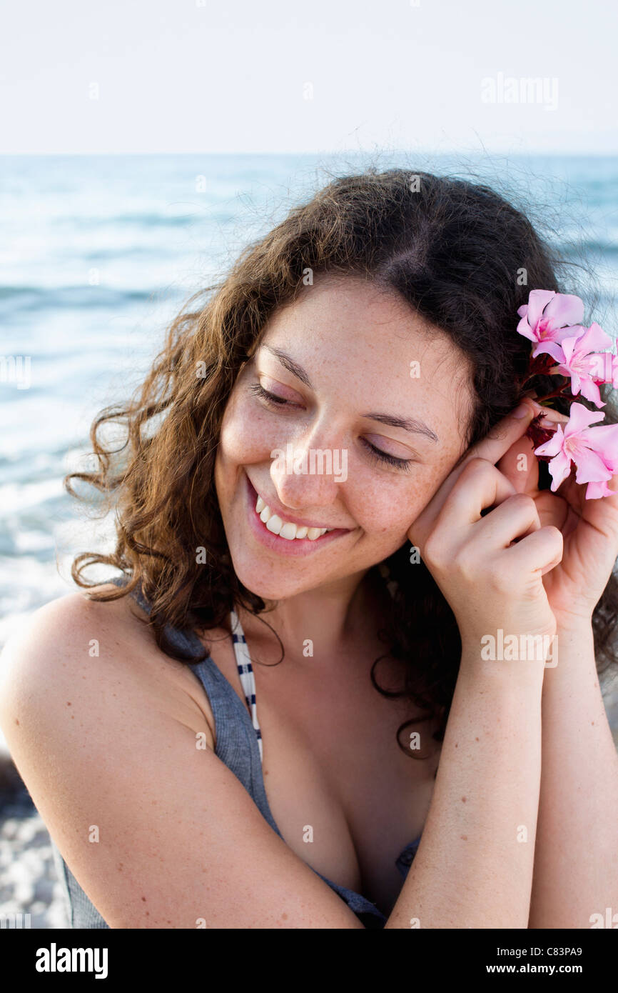 Lächelnde Frau setzen Blume im Haar Stockfoto