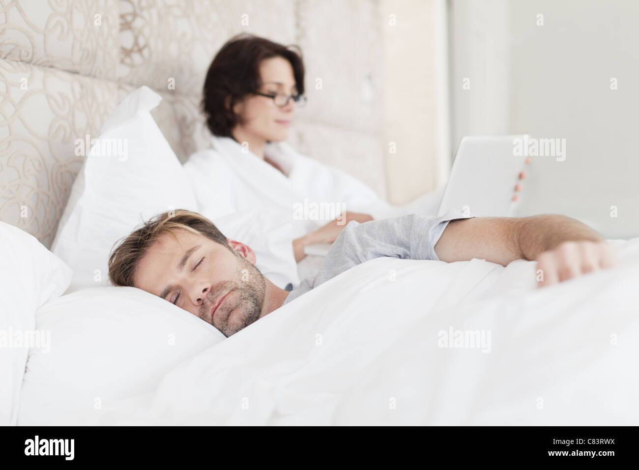 Mann schläft neben Arbeiten Freundin Stockfoto