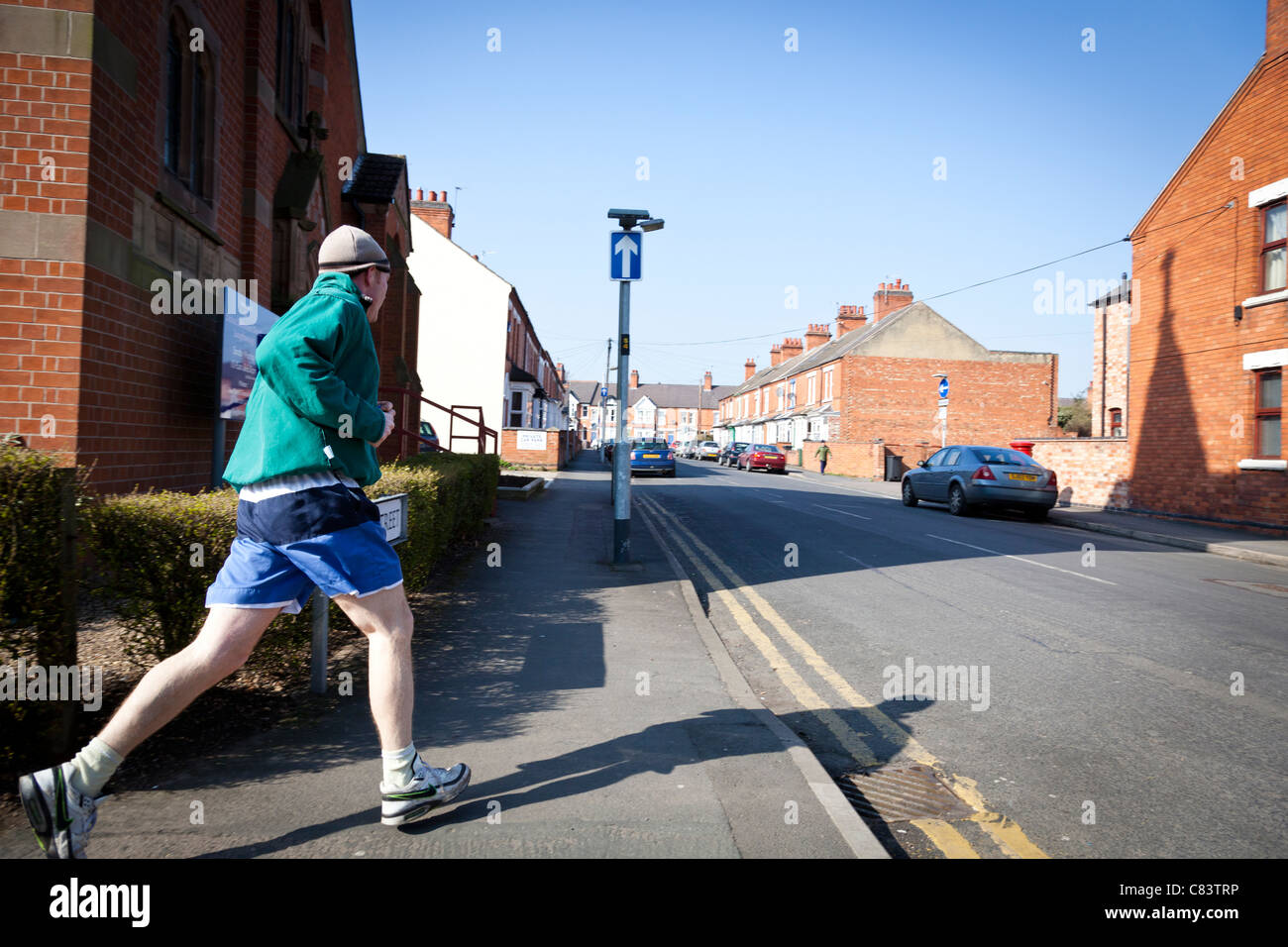 Jogger macht eine Ecke weiter seinen Lauf entlang einer Straße, England. Stockfoto