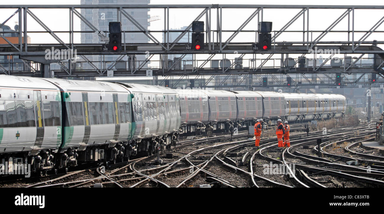 Gruppe von Eisenbahnarbeitern auf elektrifiziertem Gleis, die gut sichtbare Kleidung tragen Züge, die vom Bahnhof London Bridge in England ankommen Stockfoto