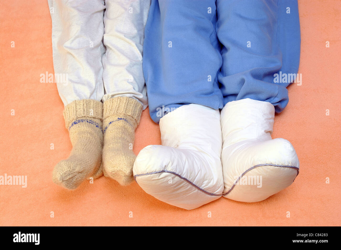 Zwei Paar Füße Erwärmung auf ein Bett Schlafzimmer Bettdecke blau genießen Fuß Hitze heiß Haus innen faul Bein lebenden orange paar pi Stockfoto